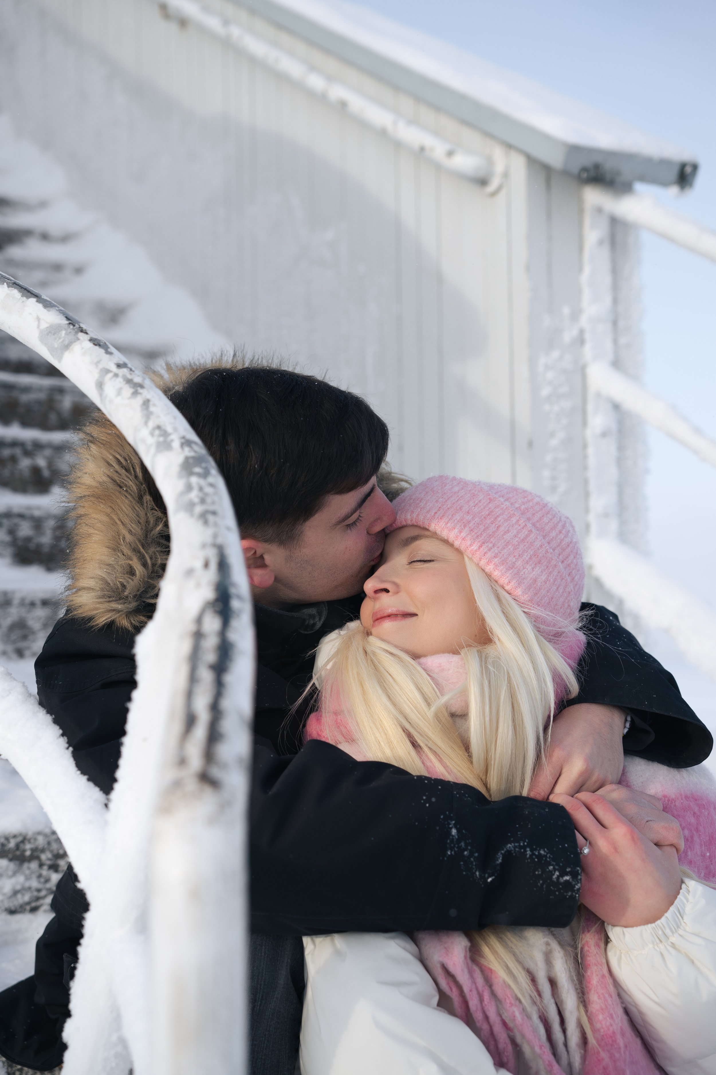 Pariskunta halailee lumisessa maisemassa parikuvauksissa