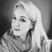 Black and white photo of a young woman with light-colored hair, wearing a hoodie, looking at the camera with a slight smile.