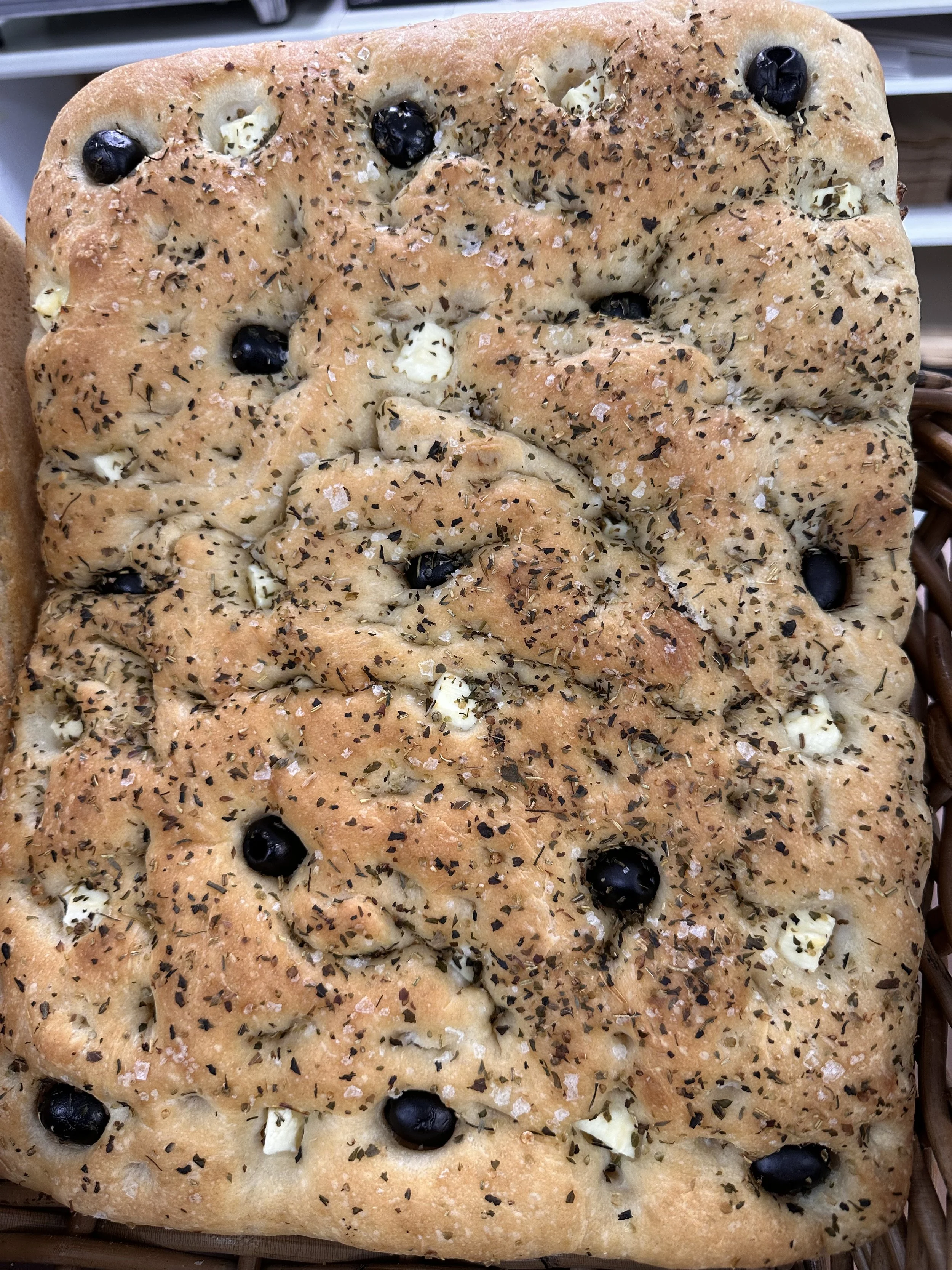 Et brett med ferskt ostebrød med sorte oliven og krydder