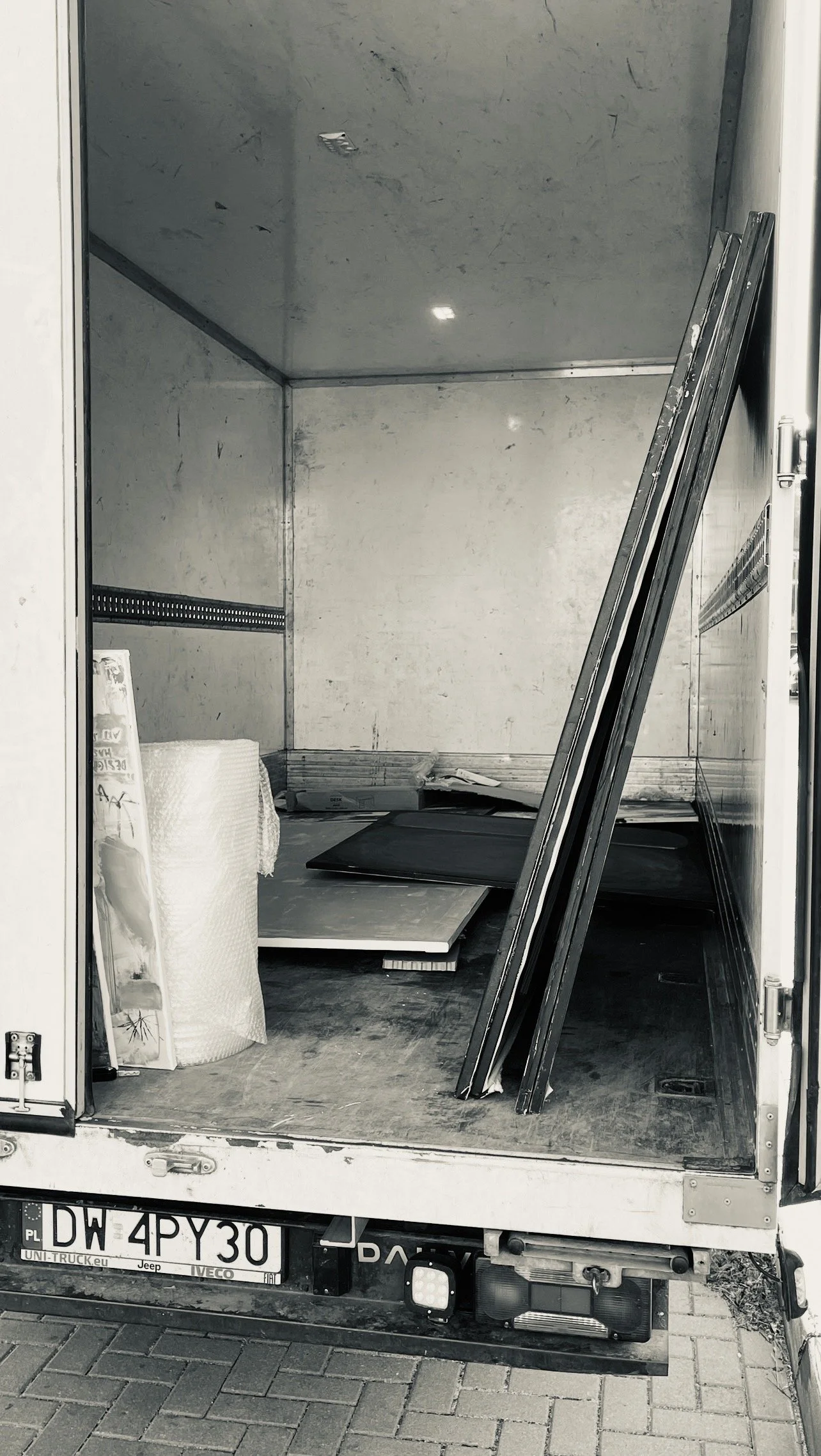 The back of an empty moving truck with a few flat panels, tools, and bubble wrap inside.