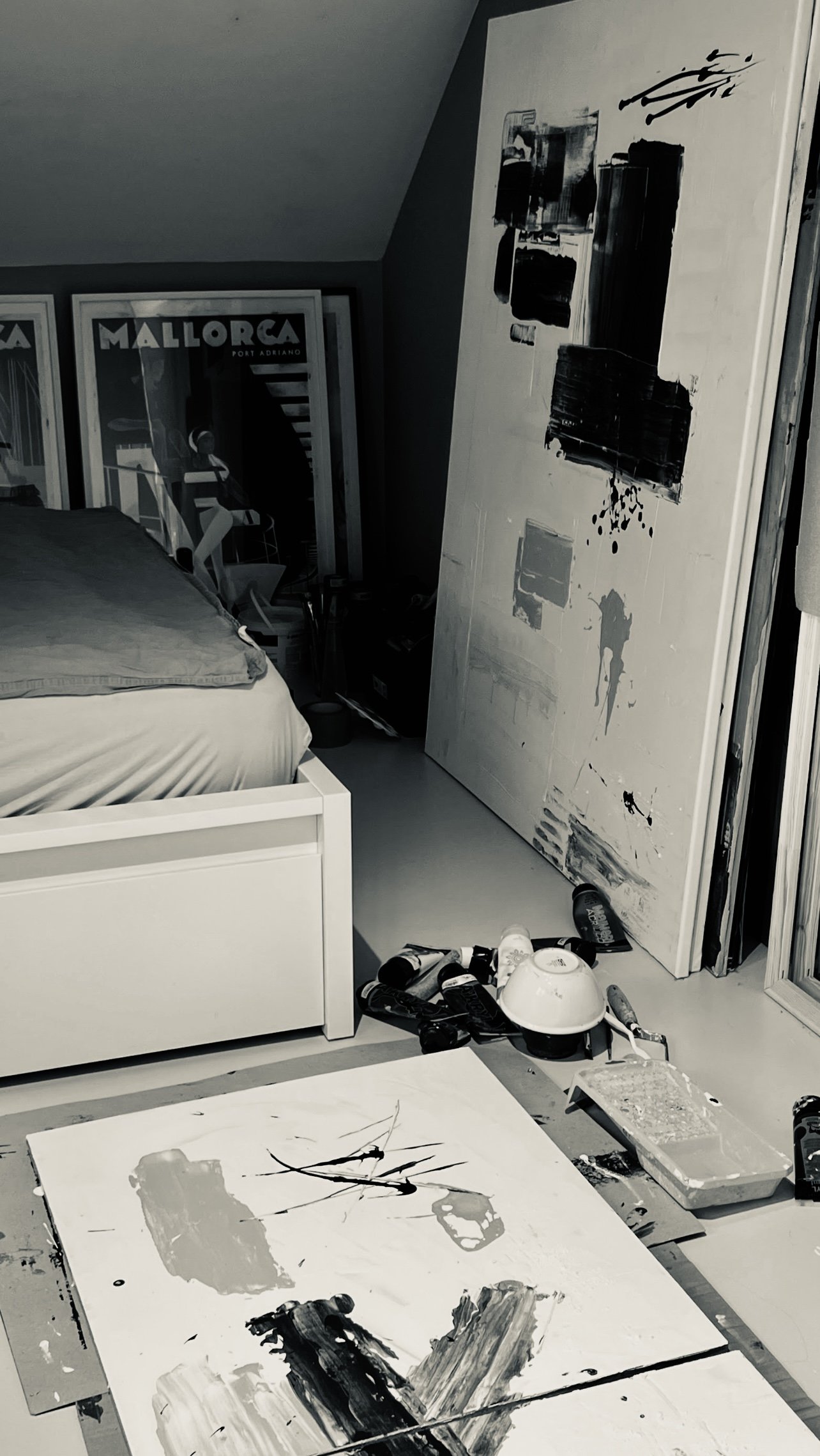 An artist's studio with abstract paintings, paint supplies, and canvases leaning against the wall.