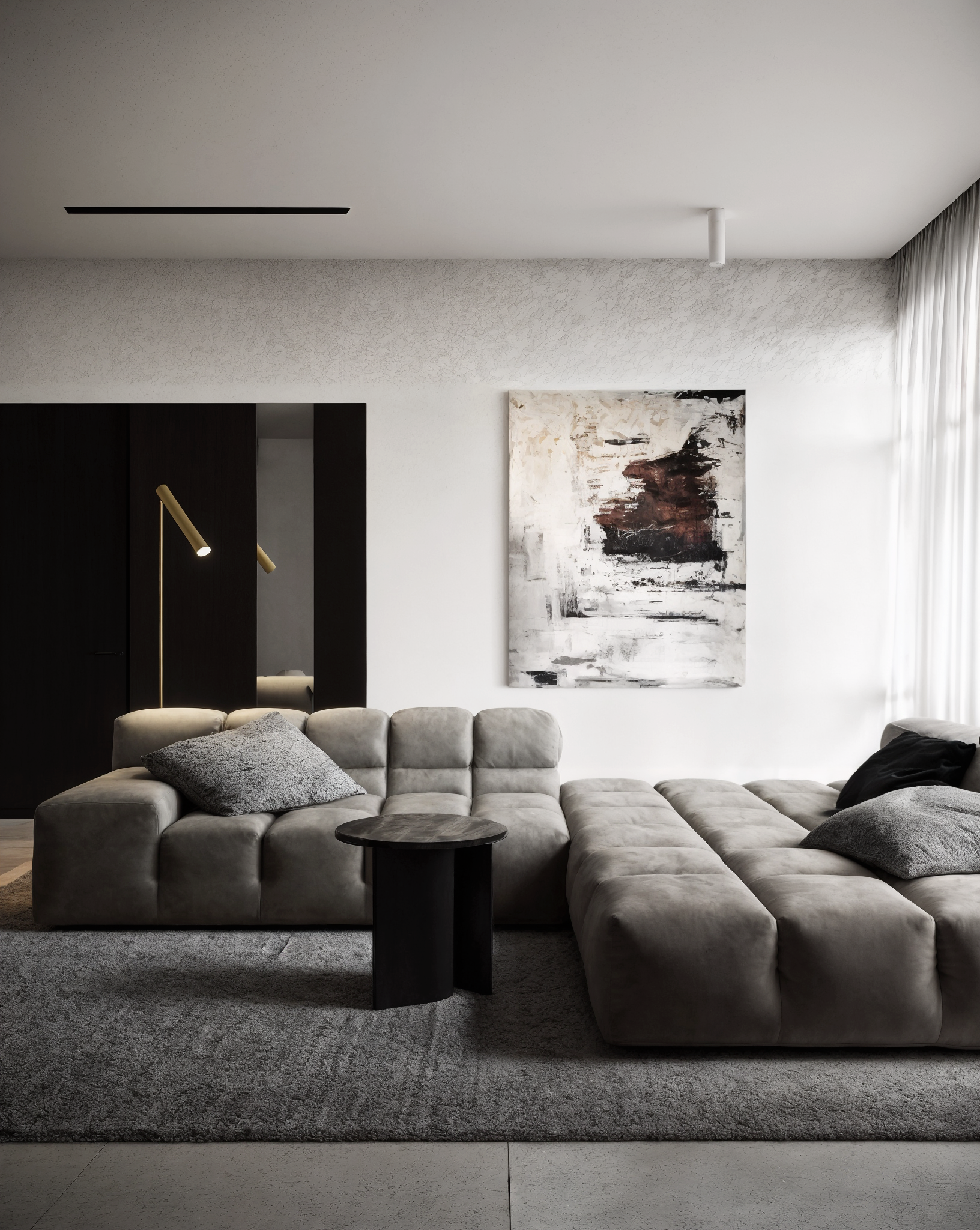 Modern living room with a large beige sectional sofa, gray pillows, a small black side table, abstract wall art, gray area rug, black wall panel with a yellow floor lamp, and white curtains.