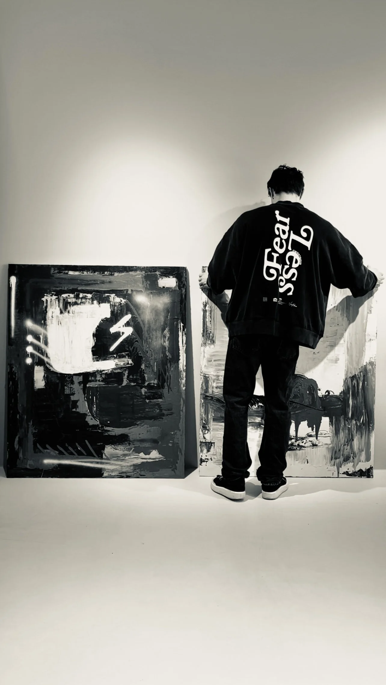 Person viewing abstract black and white paintings in an art gallery.