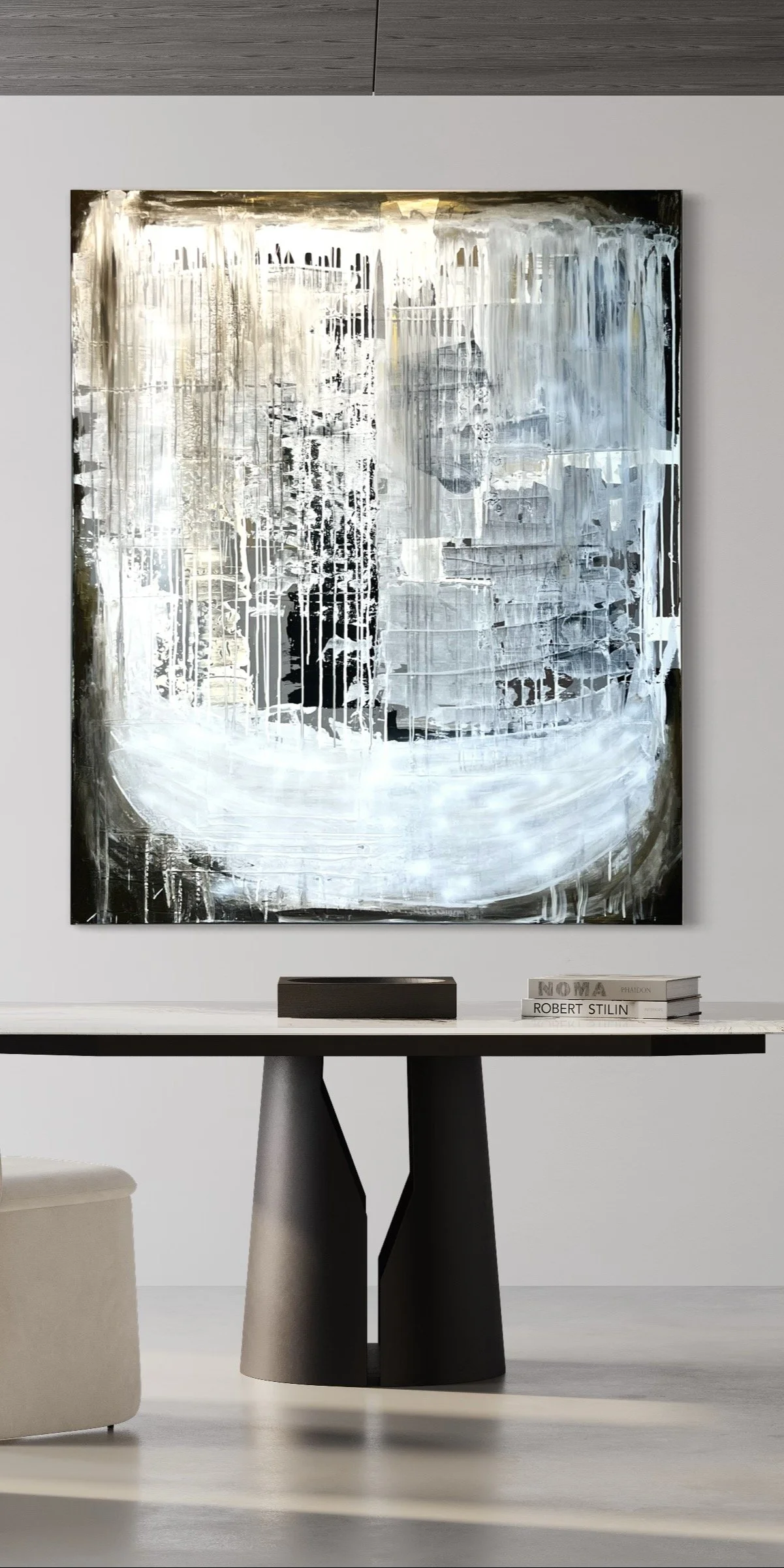 Modern abstract black and white painting hanging above a black table with books on it, in a minimalist room.