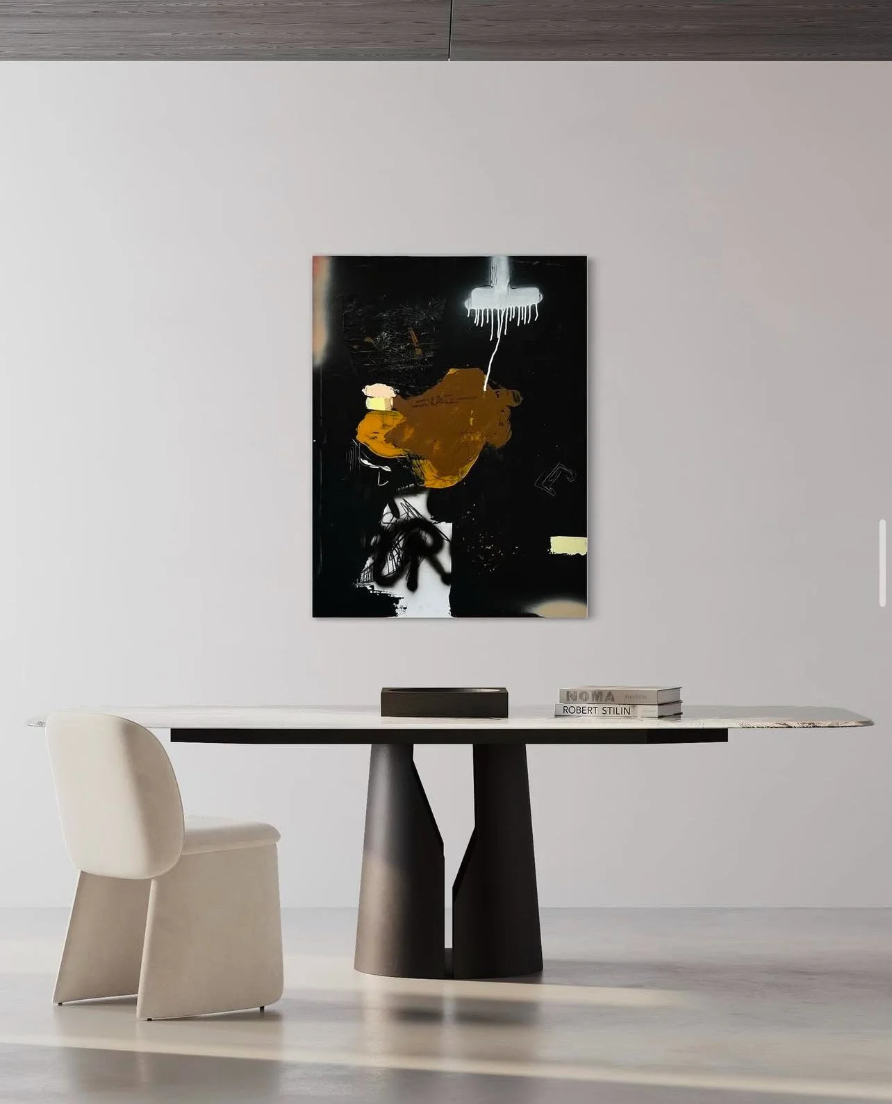 Modern minimalist room with white wall, black and white table on black base, a cream-colored chair, a large abstract black and white painting on the wall, and a stack of books on the table.