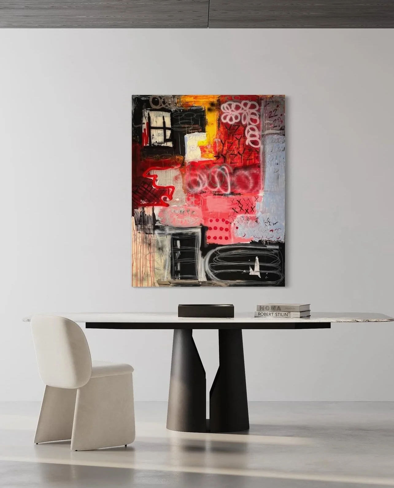 Minimalist room with white wall, abstract colorful painting, white chair, black table, and stacked books.