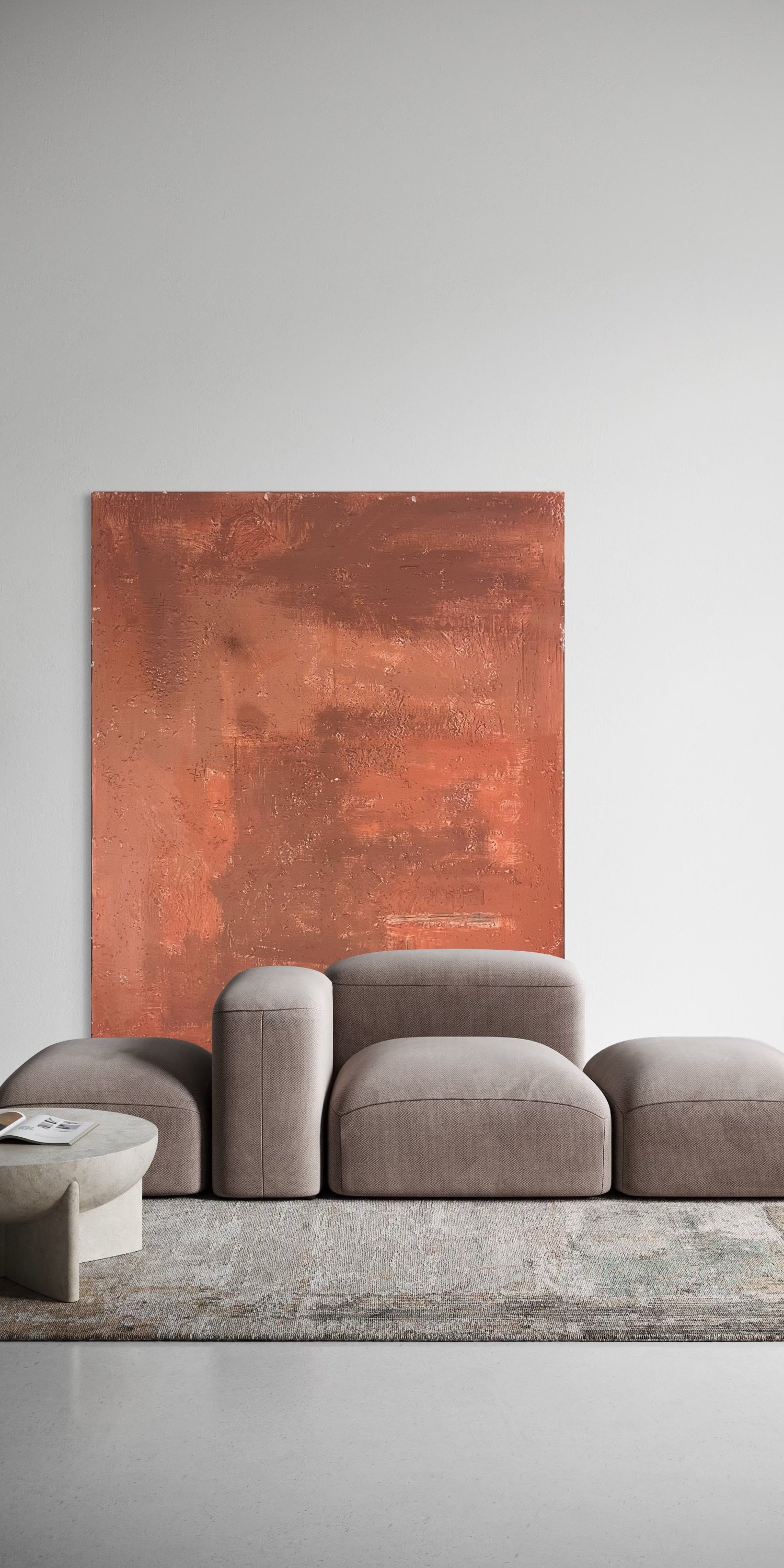 Minimalist living room with a beige sofa, a round beige coffee table, a textured abstract orange wall art, and a gray patterned rug.