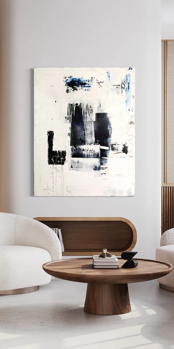 Modern living room with abstract black and white painting on the wall, white sofa, wooden coffee table, and decorative objects.