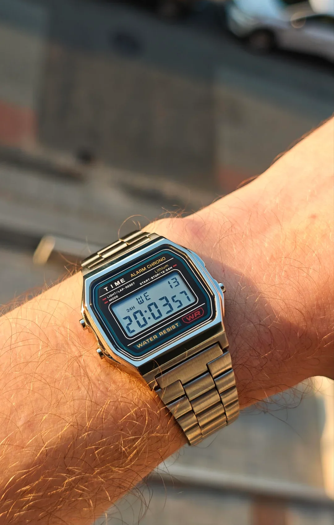 Digital wristwatch on a person's wrist showing the time 20:35:57 with a metal band and a black face.