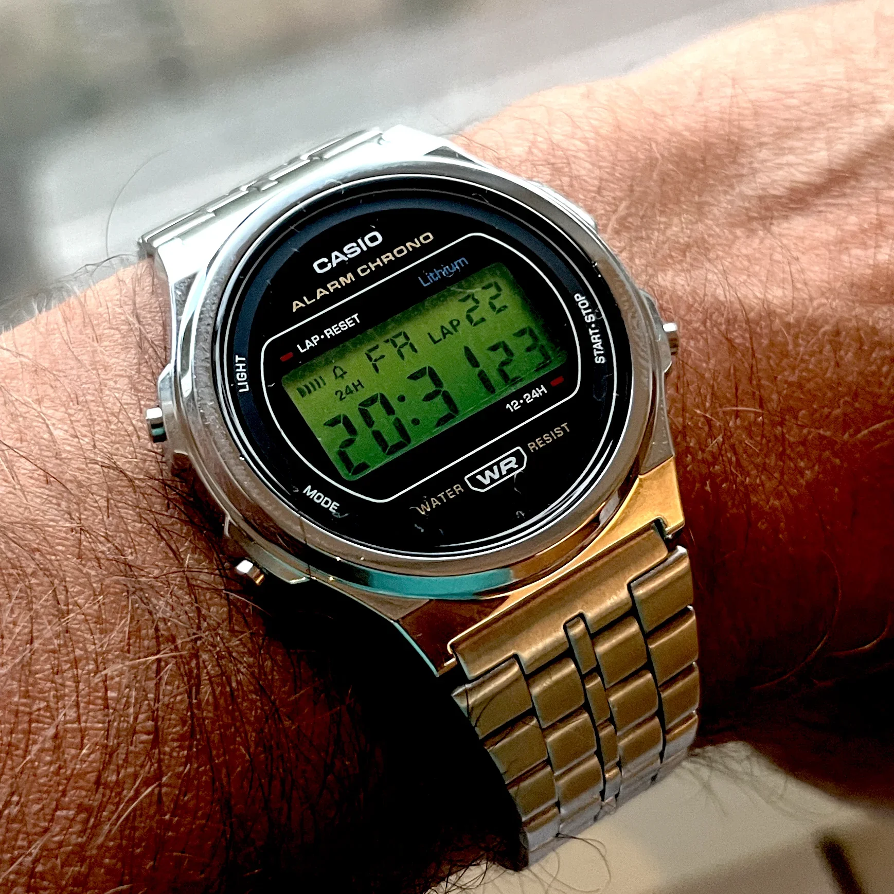 A digital wristwatch displaying the time 8:31:12, the date Friday the 22nd, and a lap time of 22.33 seconds. The watch has a silver band and black face with multiple buttons around the edge.