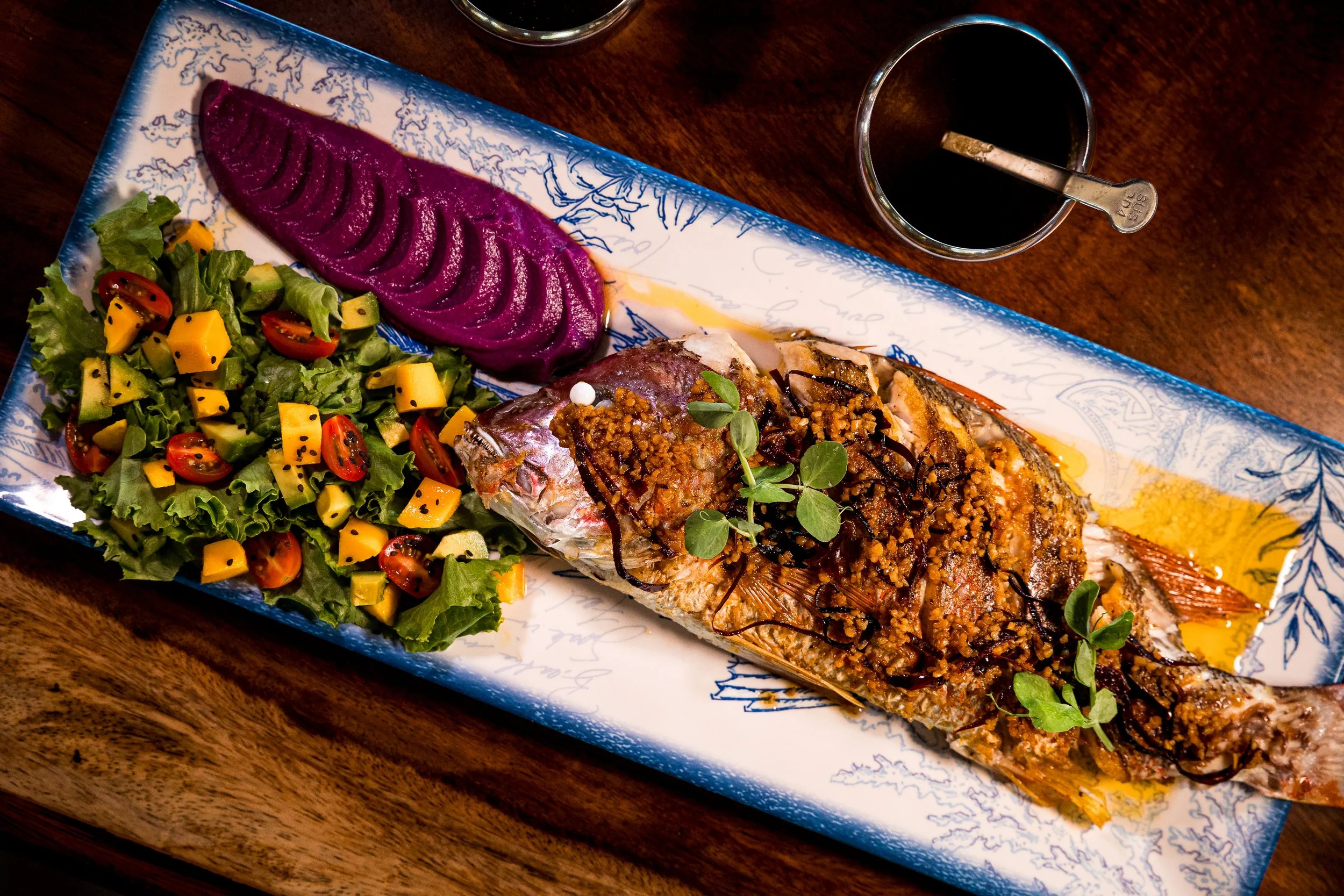 Chef-prepared whole roasted fish served with fresh mango salad and beet purée at Isla Neptuno in Puerto Escondido.