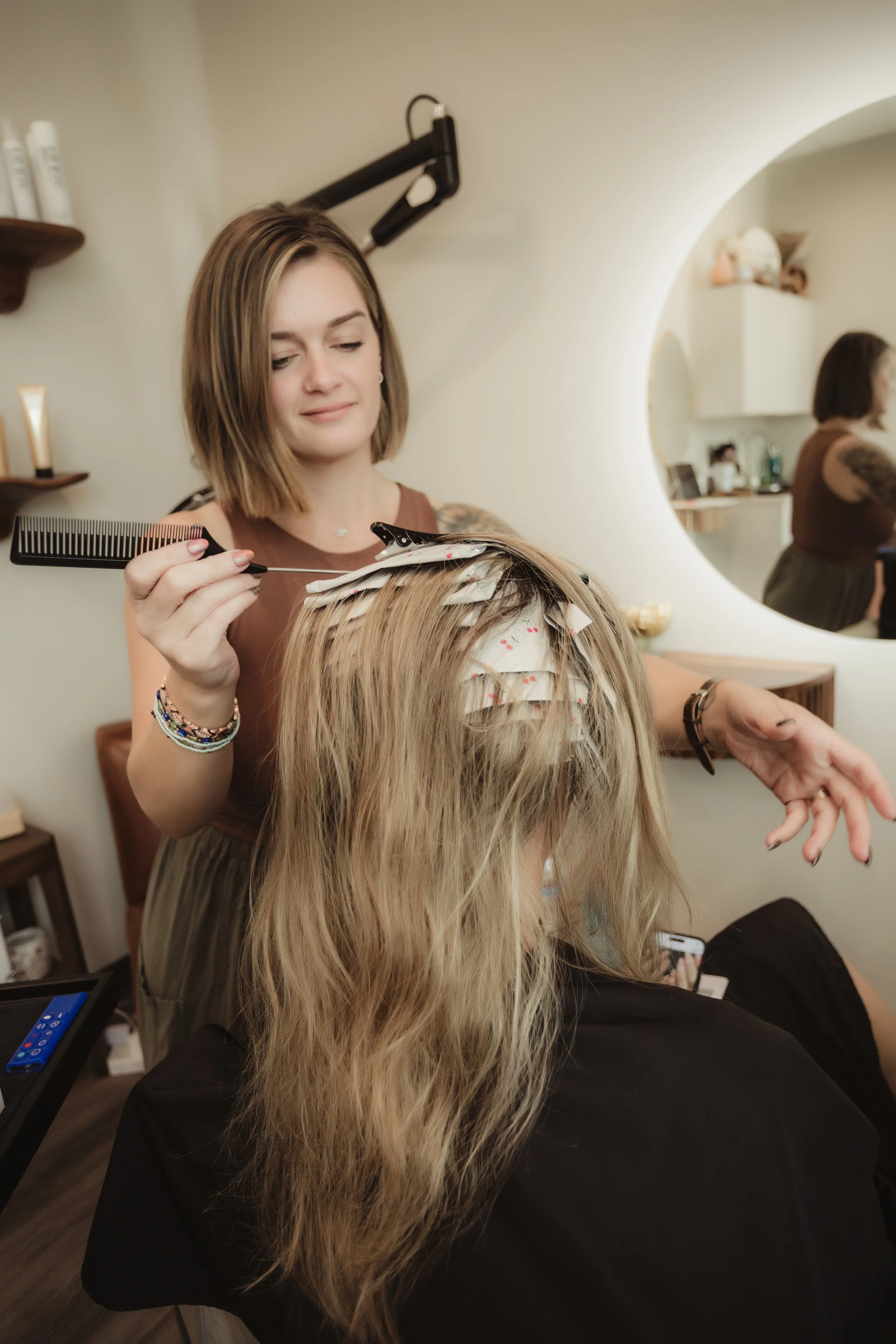 Hairdresser cutting a woman's hair with foils in her hair, in a salon.