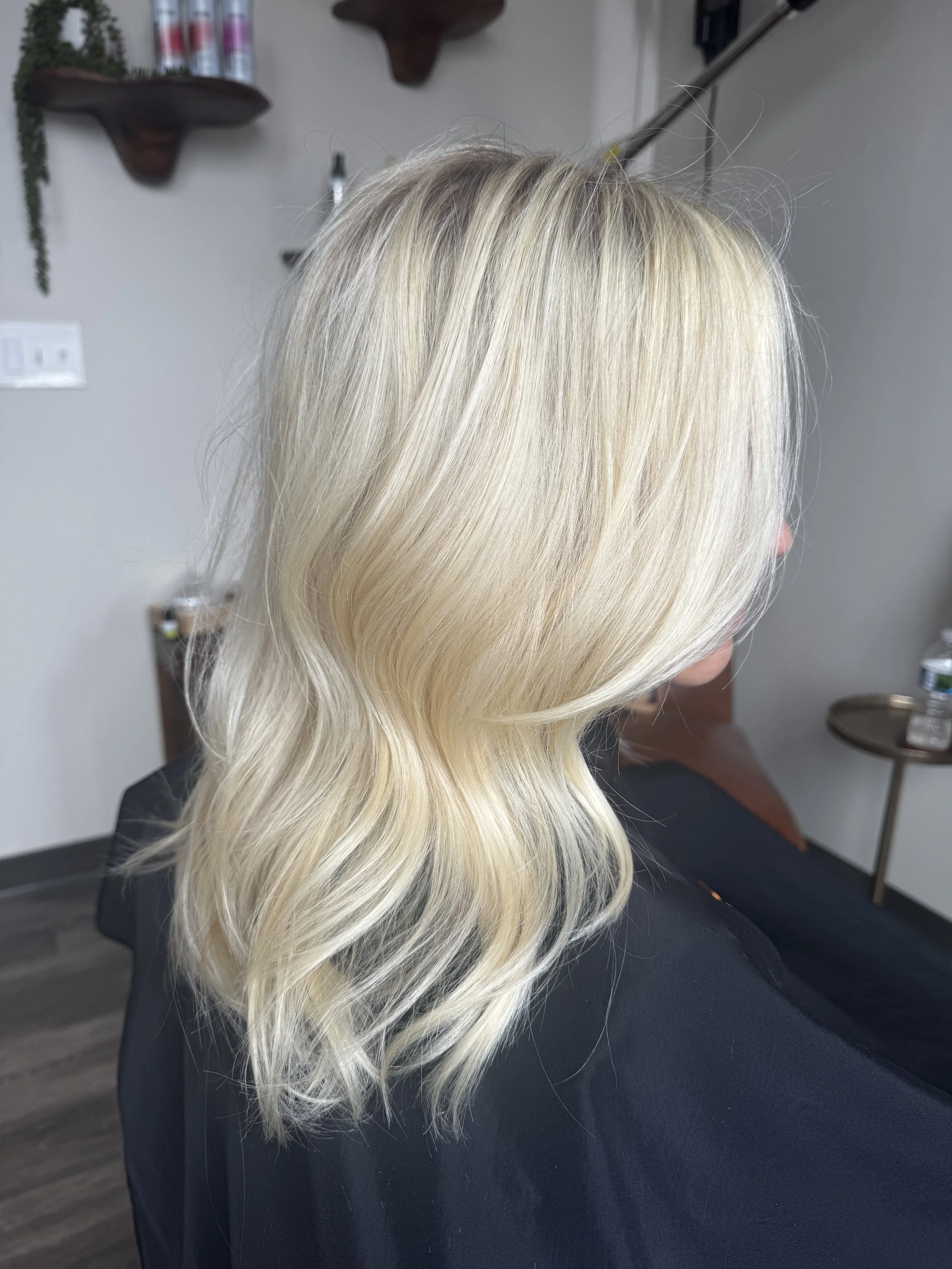 Blonde woman with wavy hair sitting in a salon seat.