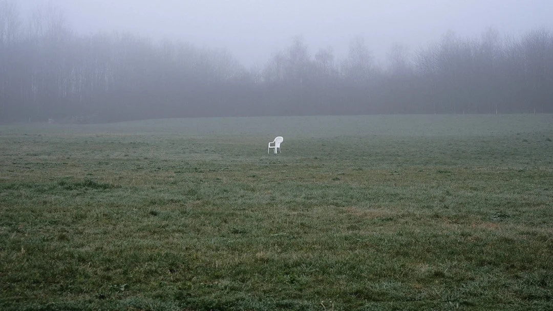 We have a dog park in my backyard area. And someone placed this cheap plastich chair right in the middle of of it. Why? I just had to take the image. A lonely chair left in the middle of the field on a dreary foggy morning.