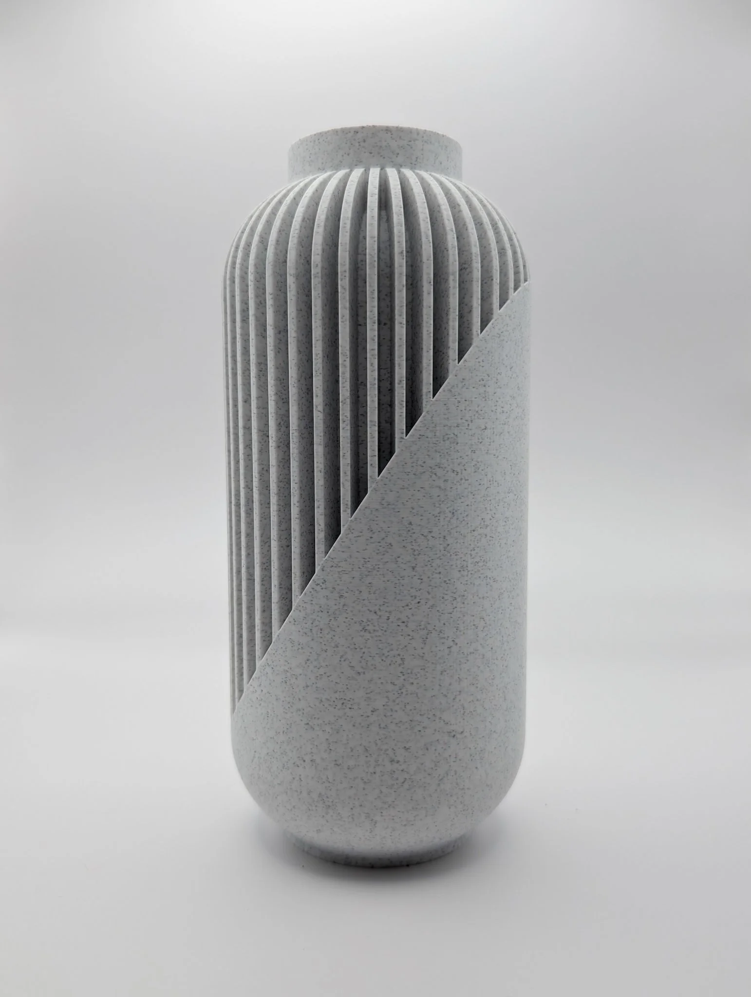 Moderne, witte architectonische sculptuur met verticale ribben en diagonale snede, tegen een effen, lichte achtergrond.