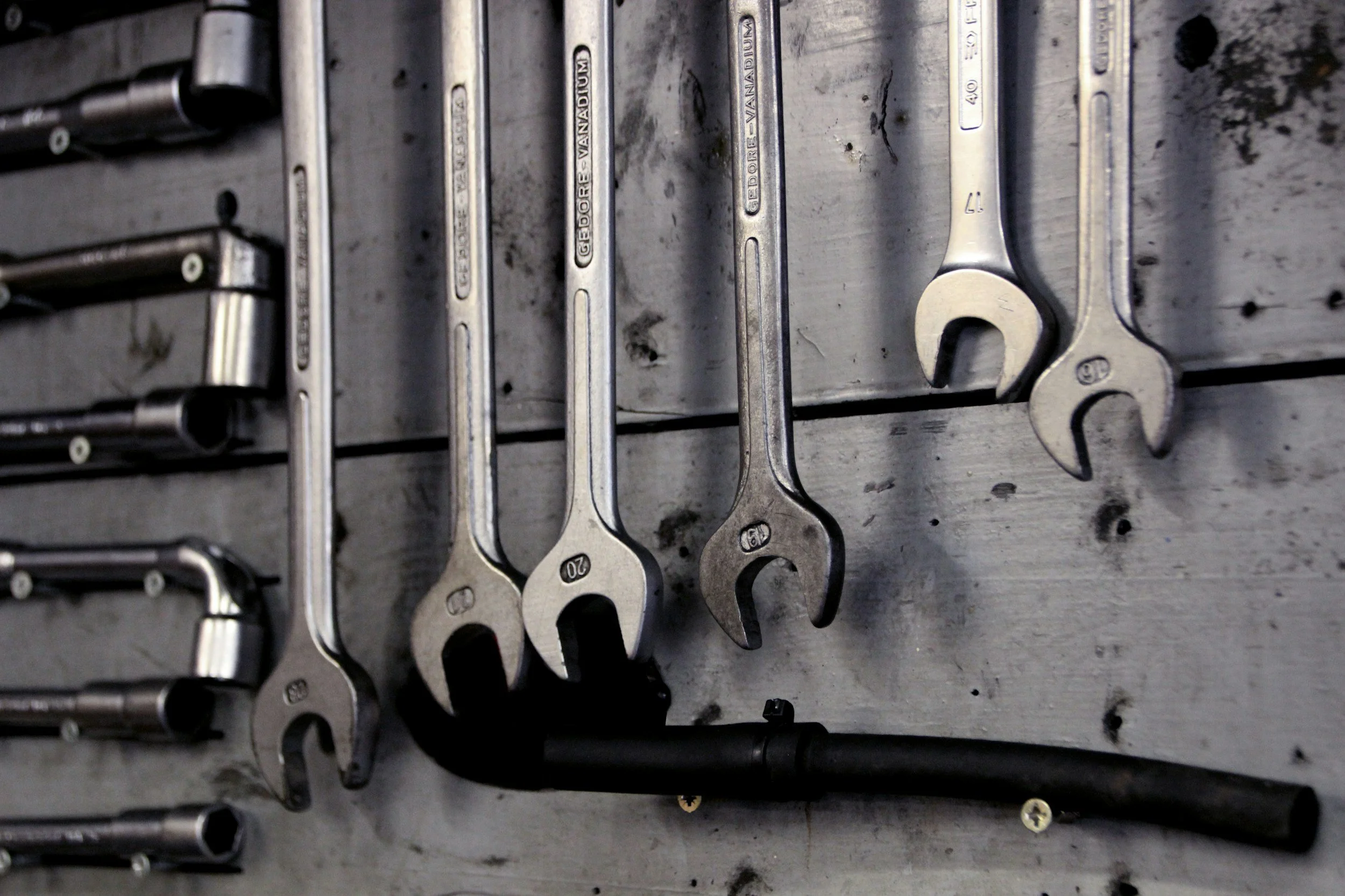 A collection of open-end wrenches of various sizes hanging on a metal rack.