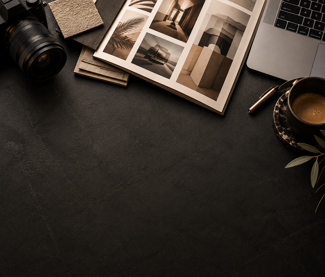 Top view of a workspace with a camera, fabric samples, an open magazine with interior design photos, a part of a laptop, a pen, and a cup of coffee on a saucer with leaves.
