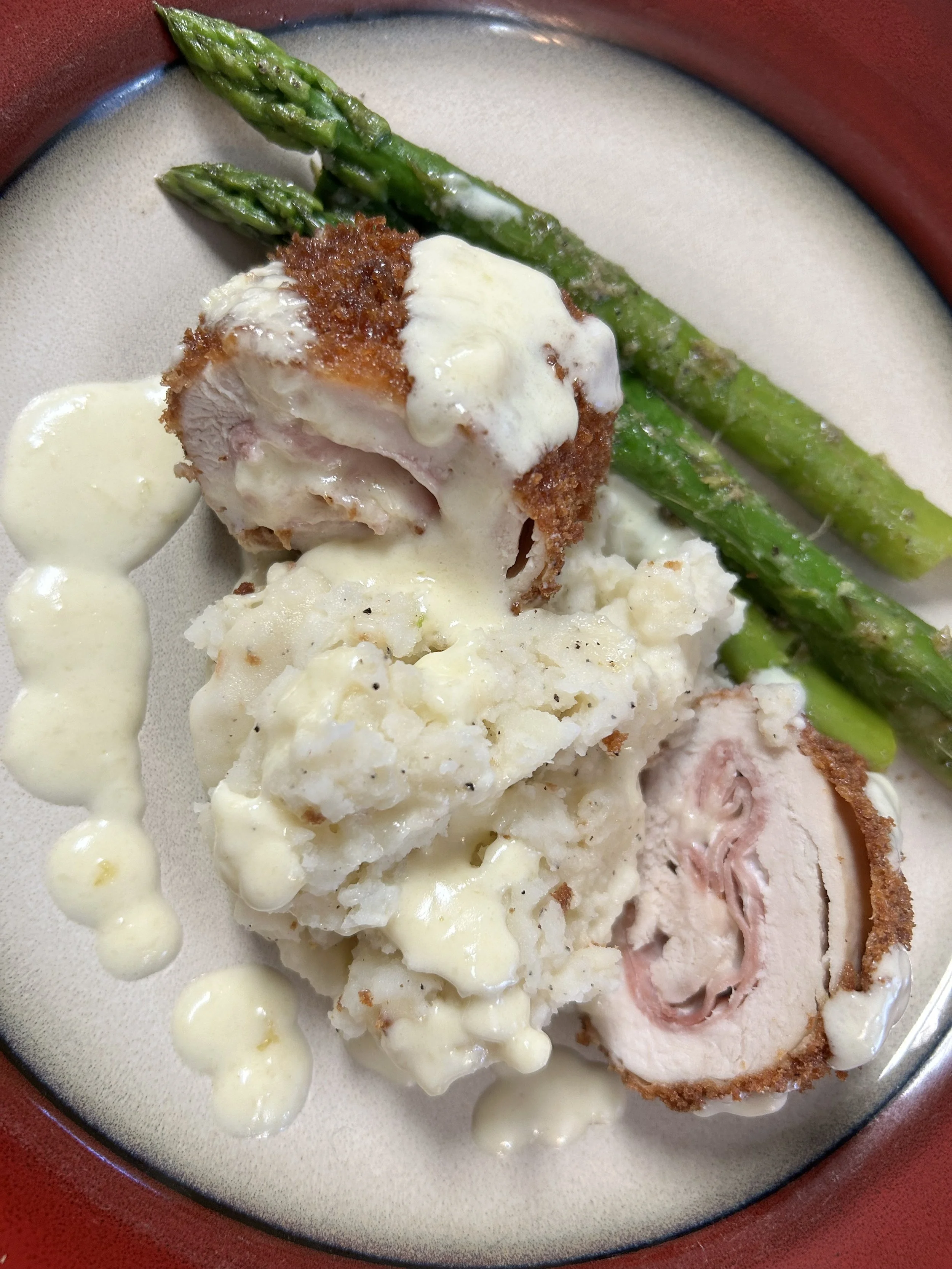 Chicken Cordon Bleu, asparagus spears, seasoned mashed potatoes, and a creamy white cheese sauce.