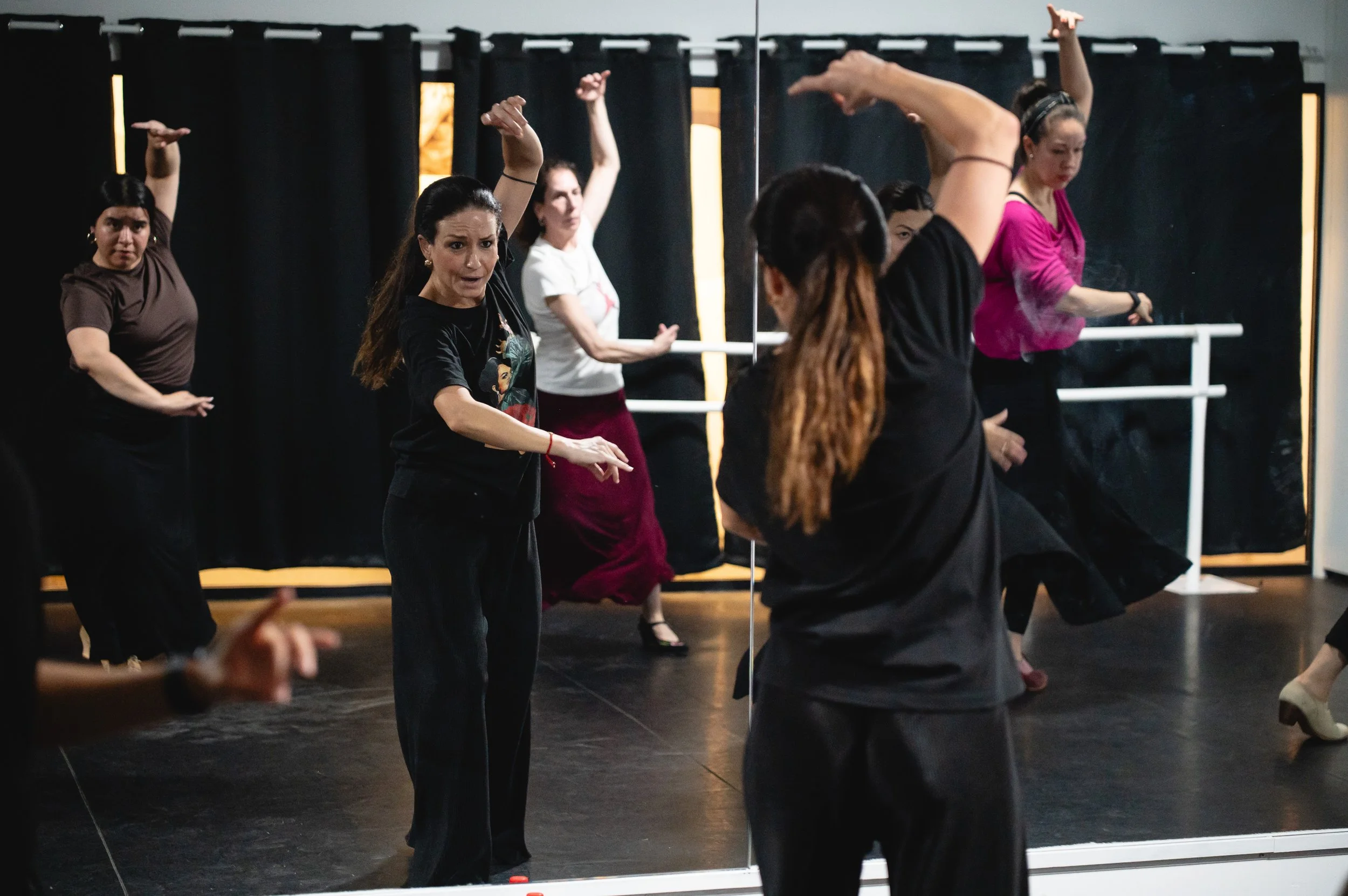 Group of women in a dance class practicing moves in front of a mirror.