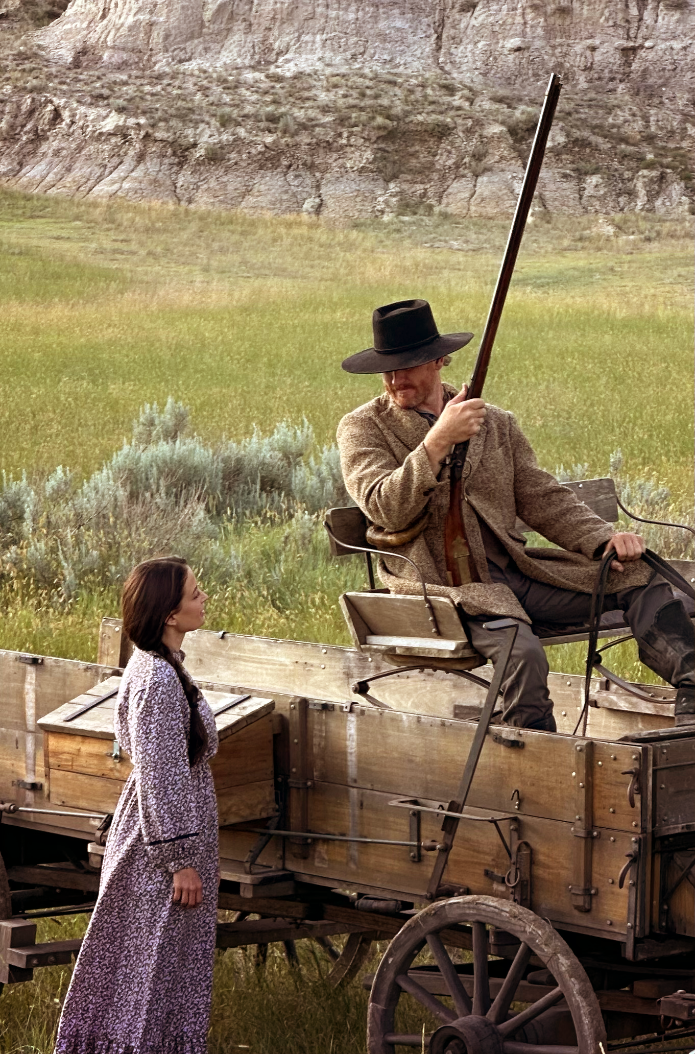 A man in a wagon looks at a pioneer woman