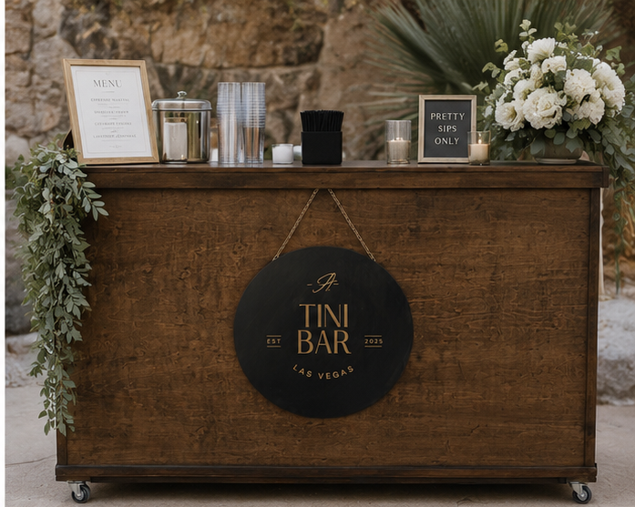 A Tini Bar's wood indoor rolling bar with a menu sign, greenery, and white roses