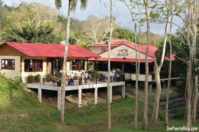 Restaurant with a red roof and outdoor patio, surrounded by tall trees