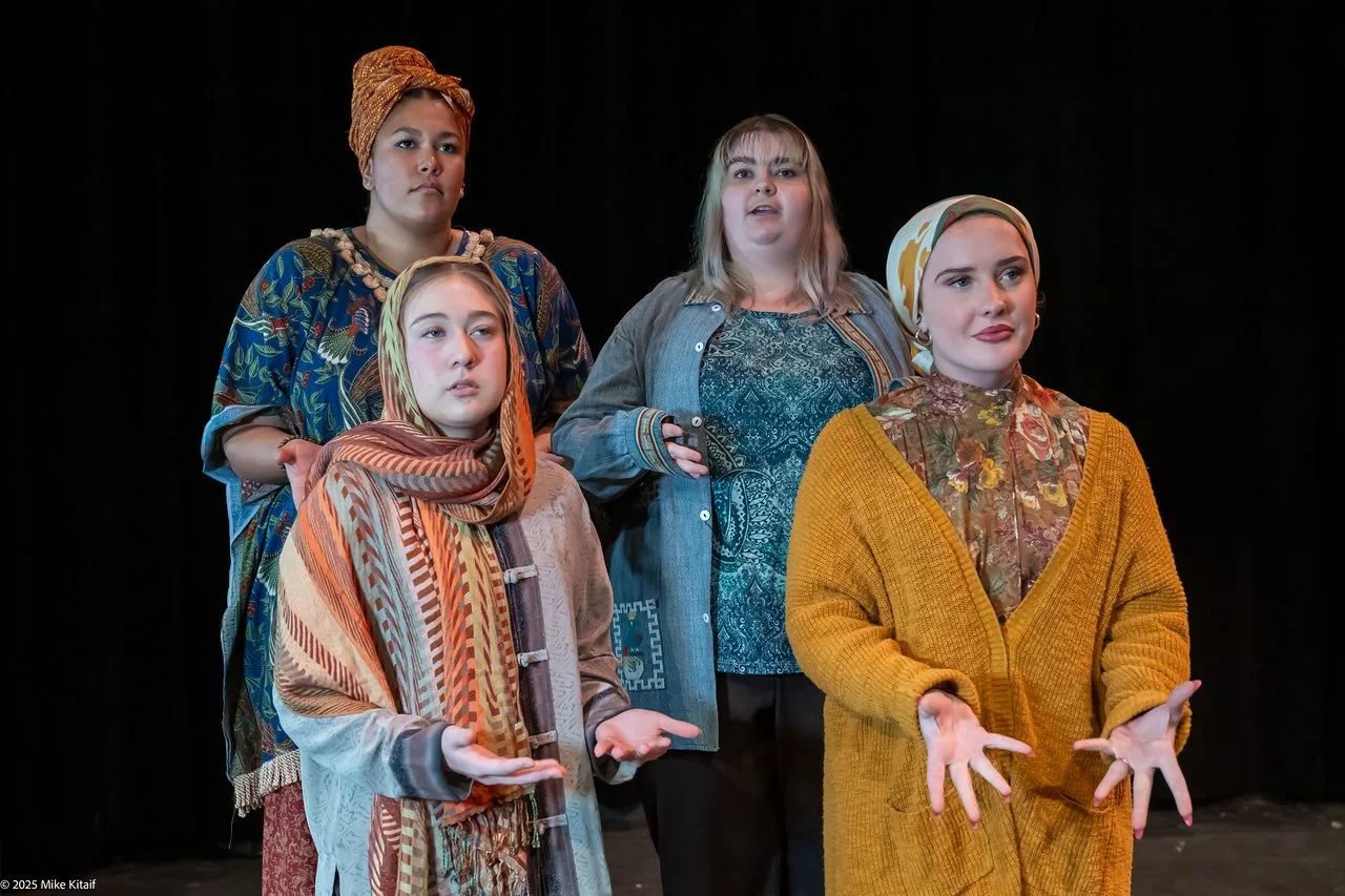 Four people in colorful costumes on stage, with dark background.
