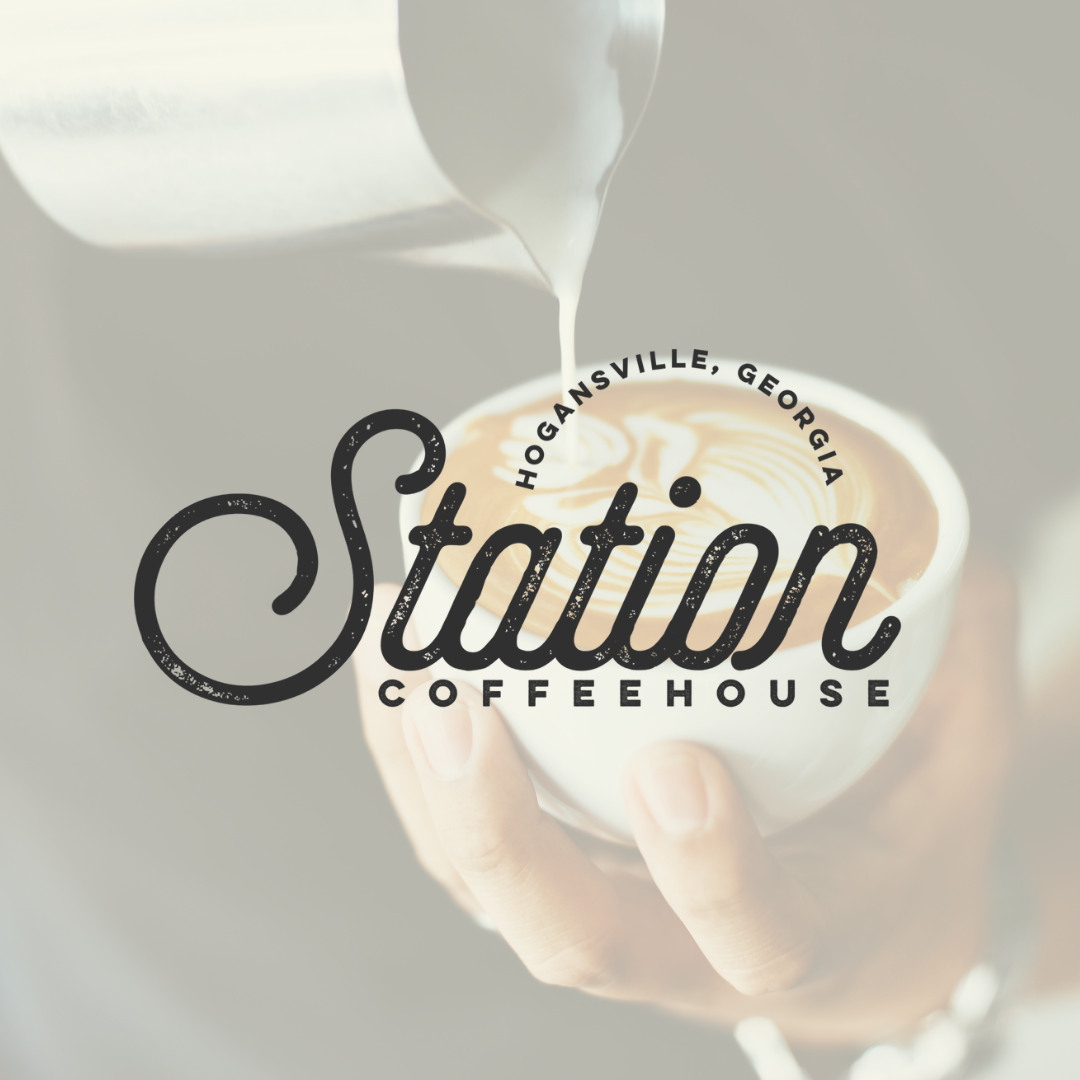 A hand holding a coffee cup with latte art, with milk being poured into it from a pitcher, and a logo for Station Coffeehouse in Hogansville, Georgia