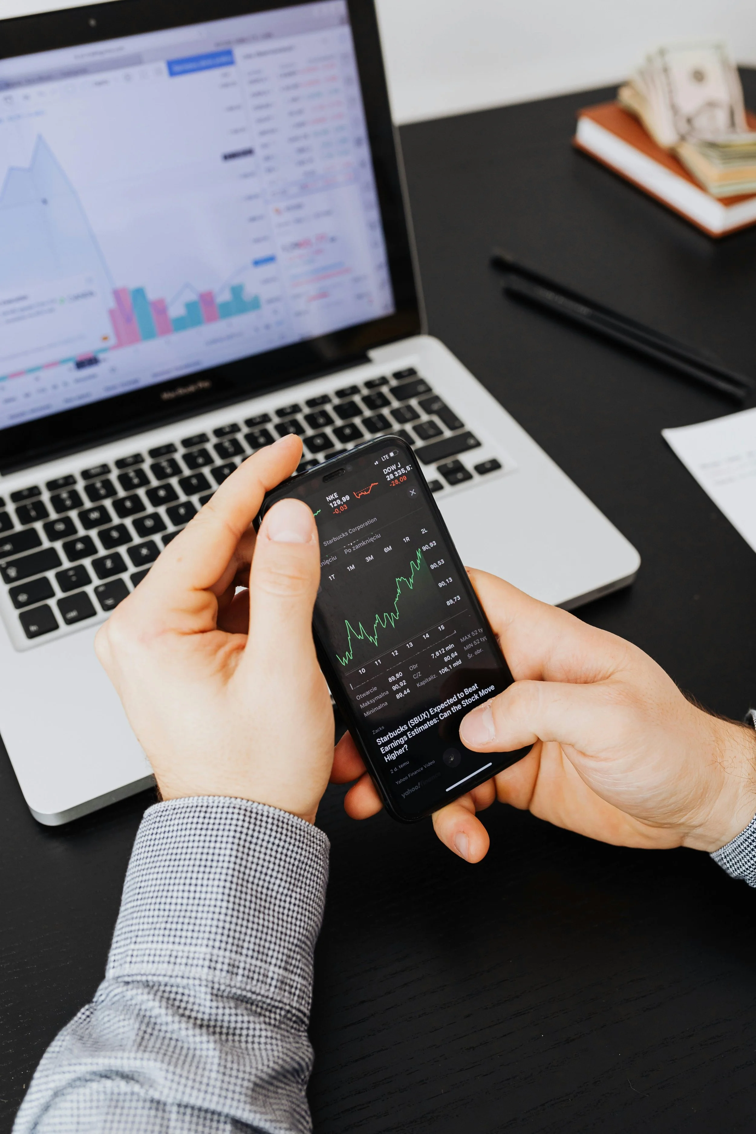 Close-up of a professional analyzing a financial dashboard on a laptop and phone, representing high-level financial reporting and data-driven insights.