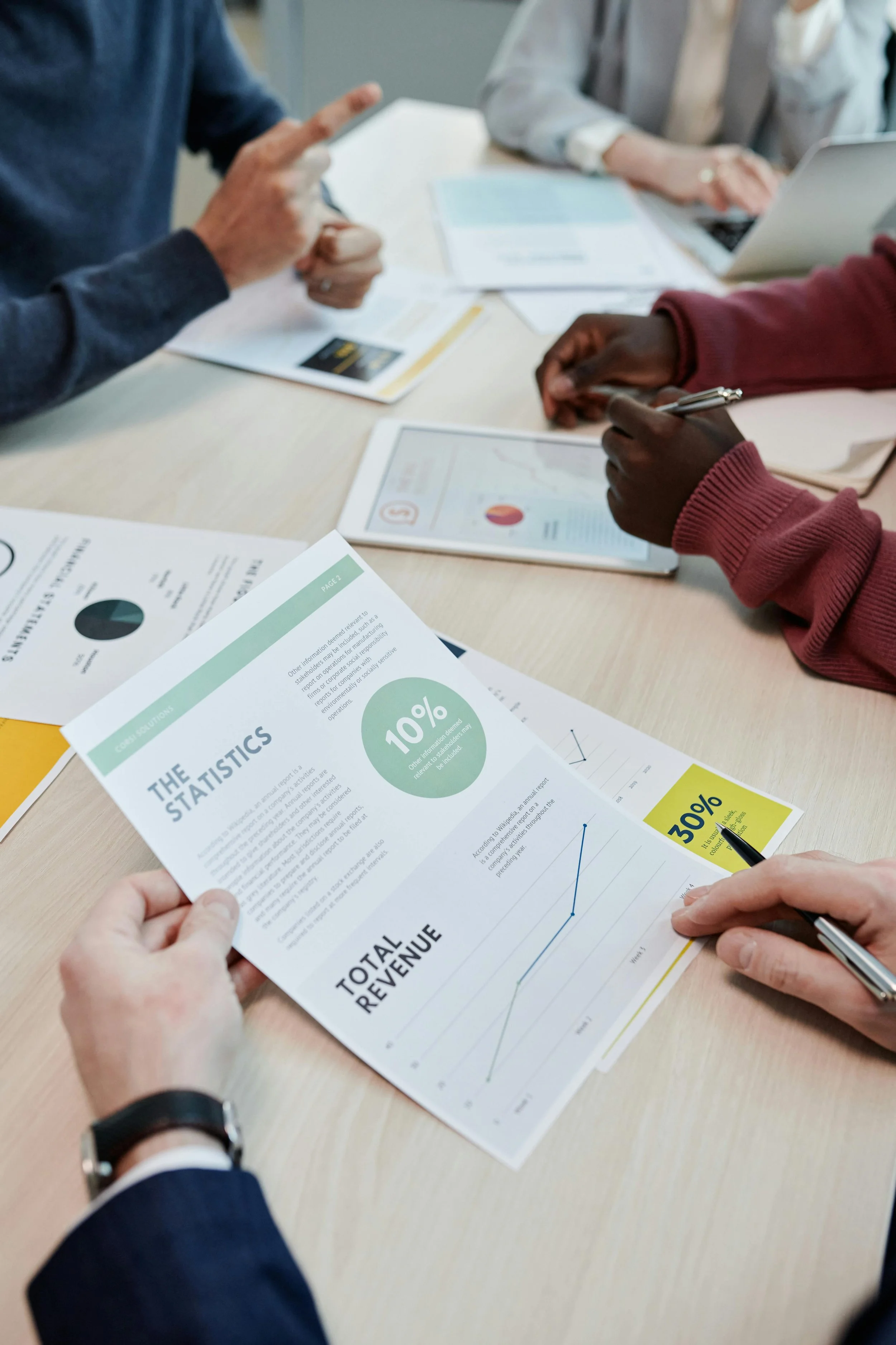 A collaborative team reviewing financial reports and spreadsheets on a table, illustrating hands-on grant tracking and professional advisory services.