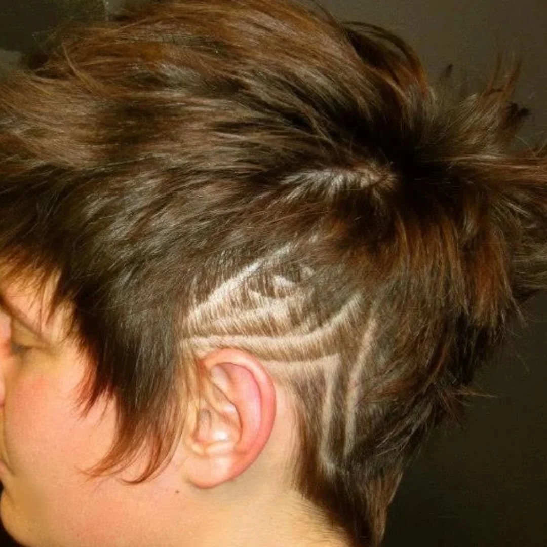 Close-up of a person with brown hair styled in a shaved-side undercut design and top bun
