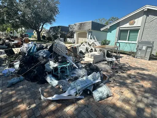 Storm debris cleanup in Spring Hill, FL with damaged furniture and household items piled at the curb by Five Alarm Dumpsters