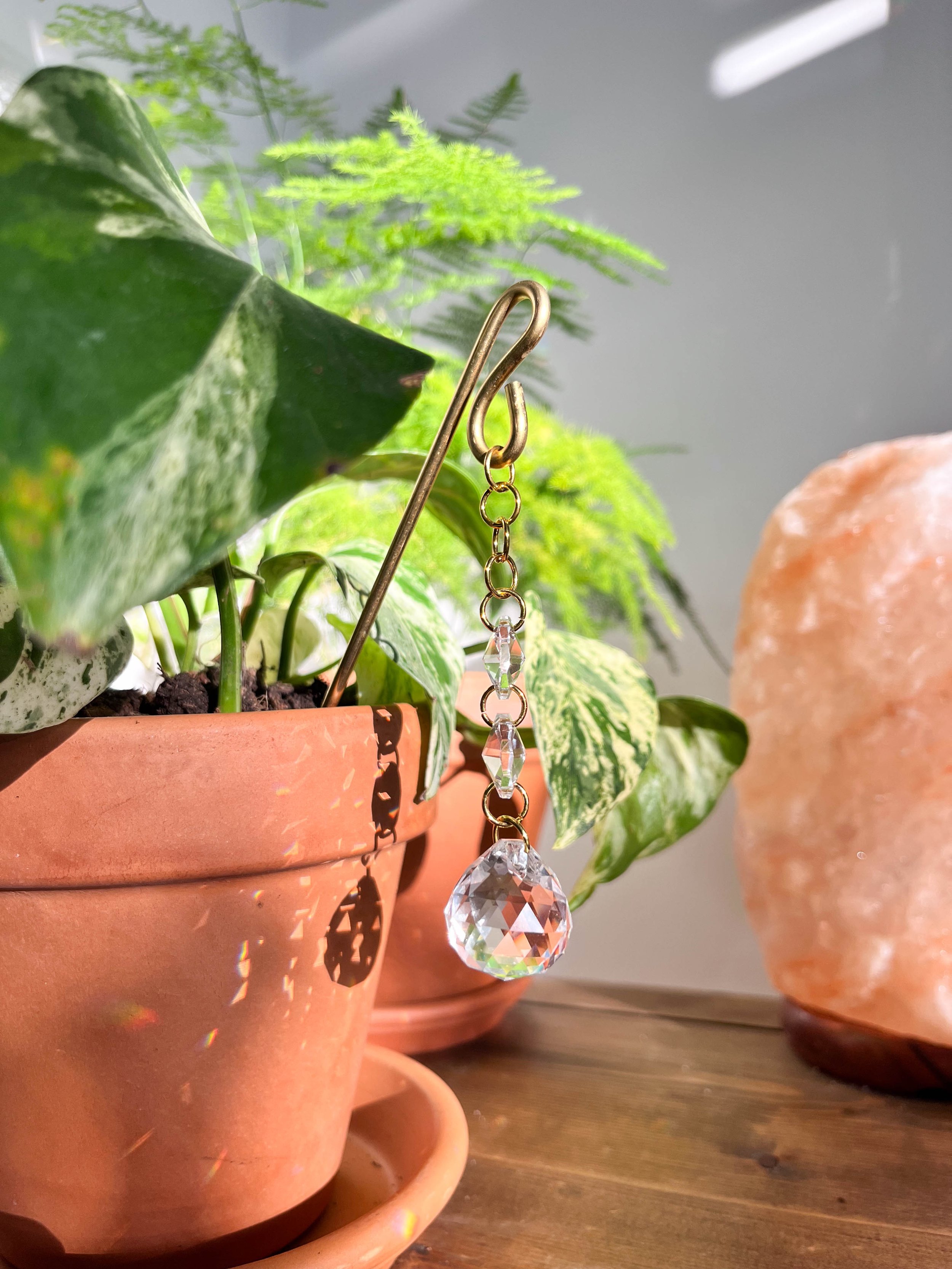 Gold chain sun catcher featuring three crystal prisms hanging delicately, perfect for catching sunlight and adding sparkle to any indoor space.