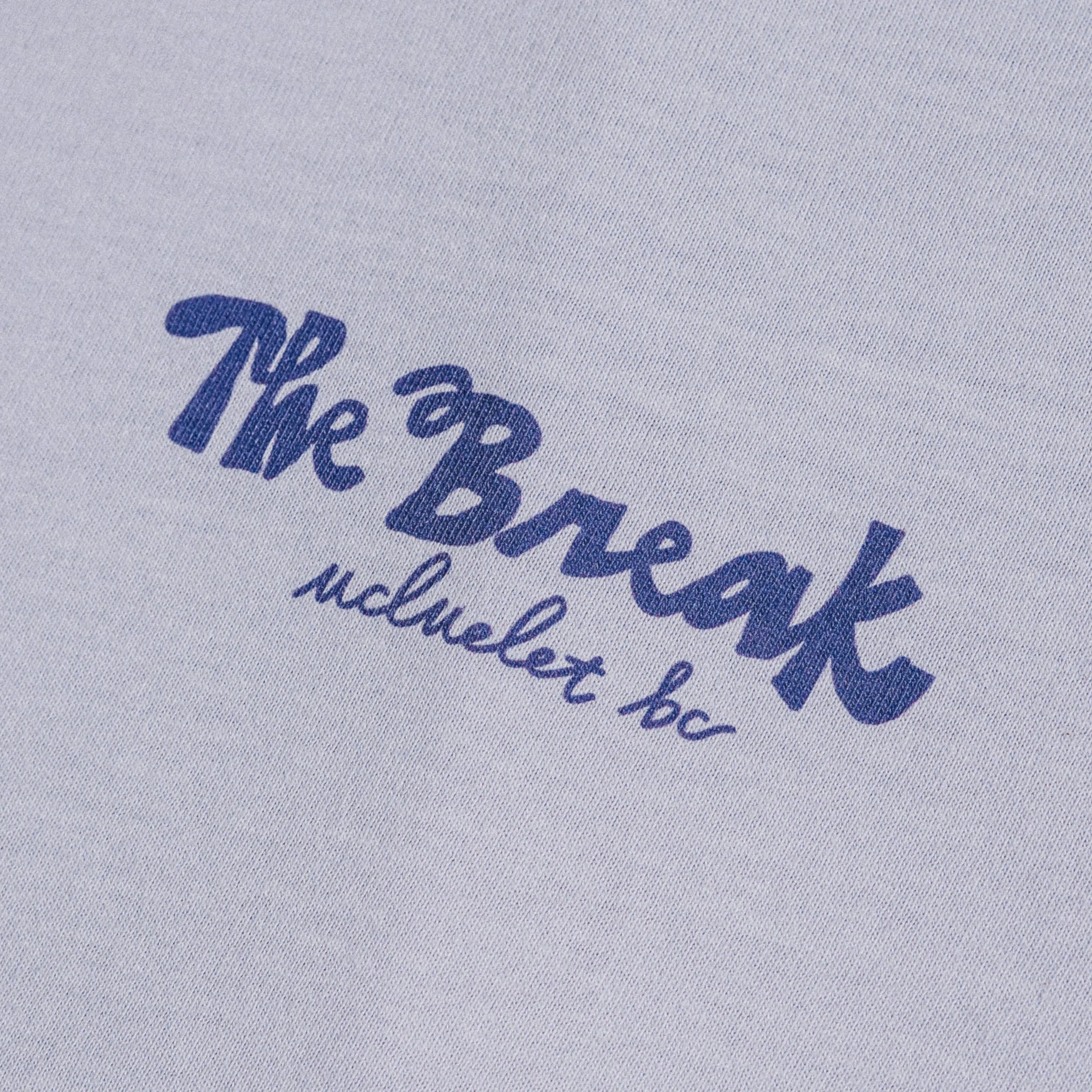 Close-up of a blue fabric with blue printed text reading 'The Break Ucluelet, BC'.