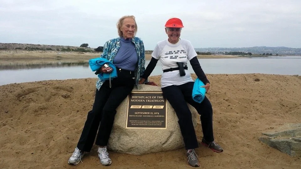 Flo Squires, 29th Finisher and Gail Hanner, 33rd Finisher of the First Triathlon at the 40th Anniversary 2014, sitting on the dedication rock, Fiesta Island, San Diego, CA. (Photo by Thao Vu)