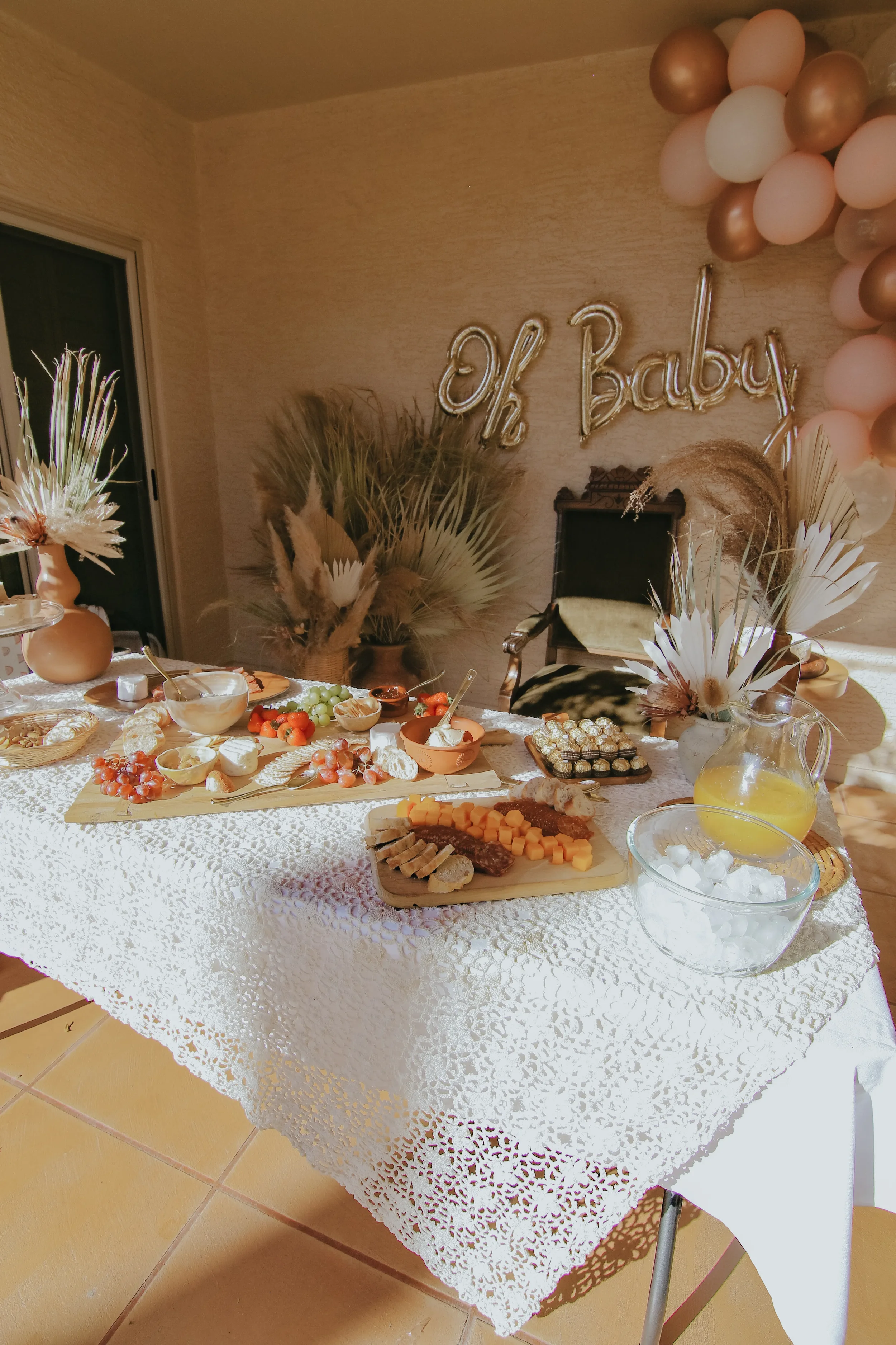 Warm boho celebration table with pampas grass, neutral linens, and soft peach balloons.