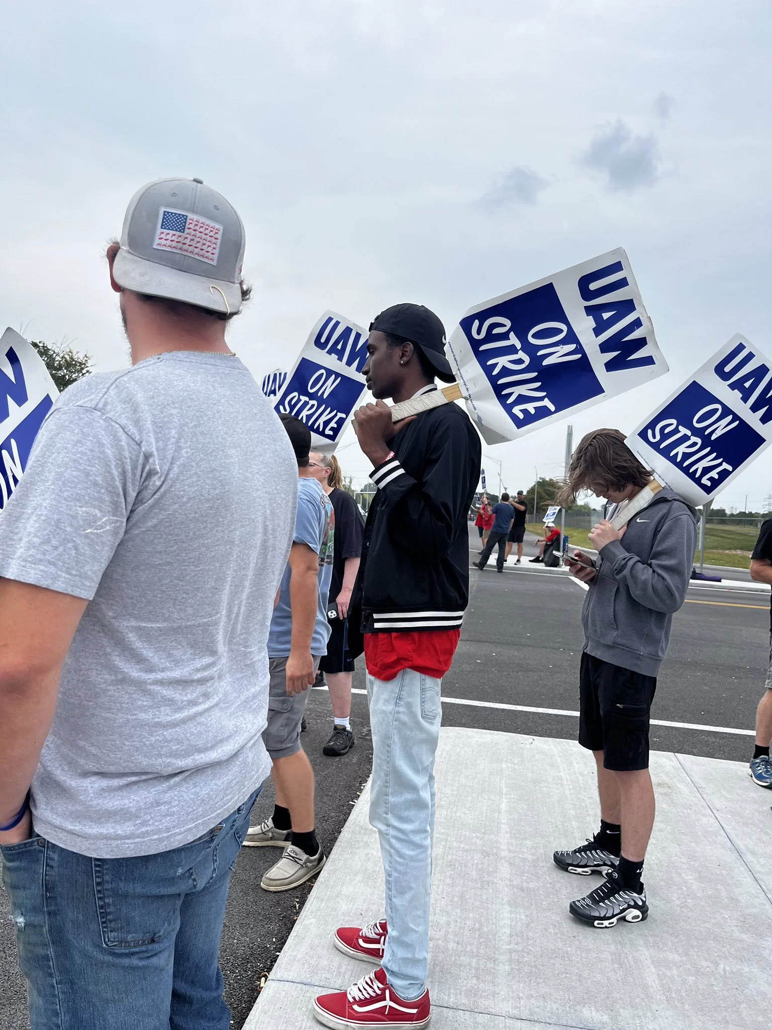 People participating in a protest holding signs that say "UAW on Strike".