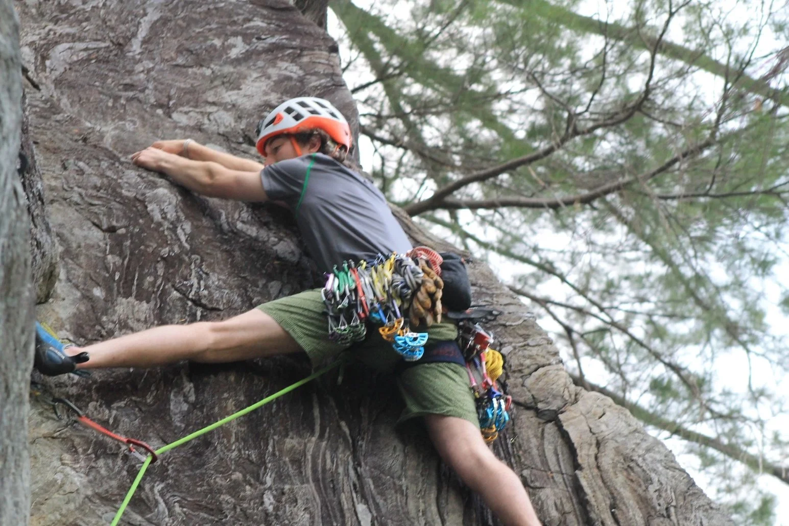 Person rock climbing on a rock face, wearing a helmet, climbing shoes, and gear