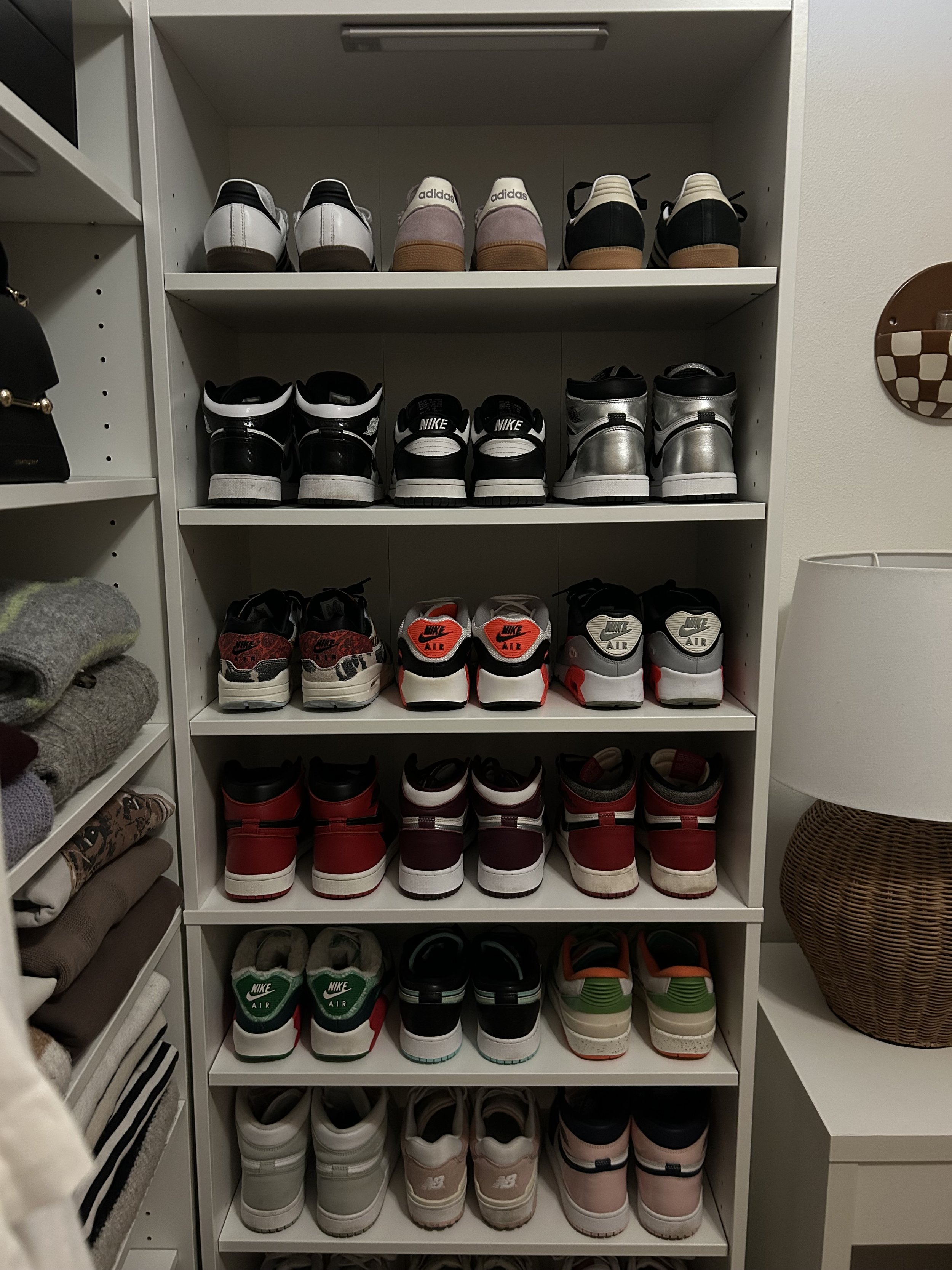A white shelving unit filled with various styles and colors of sneakers, organized in six rows.