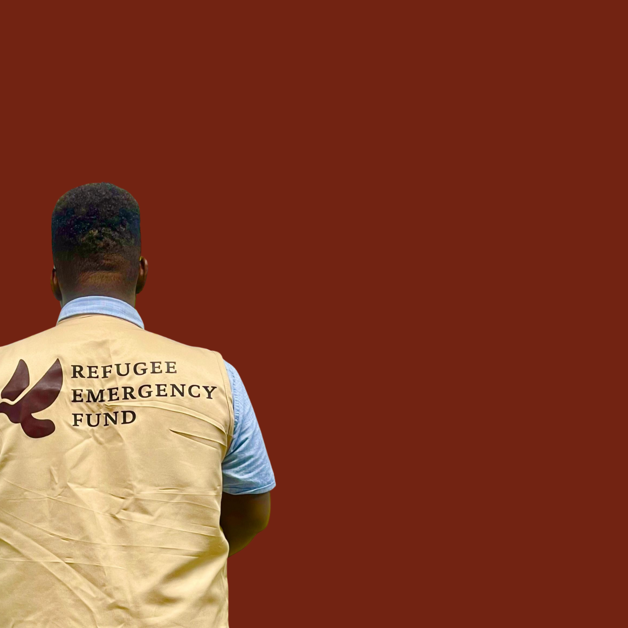 Back of a person with short hair wearing a beige vest with 'Refugee Emergency Fund' written on it, standing against a plain, dark brown background.