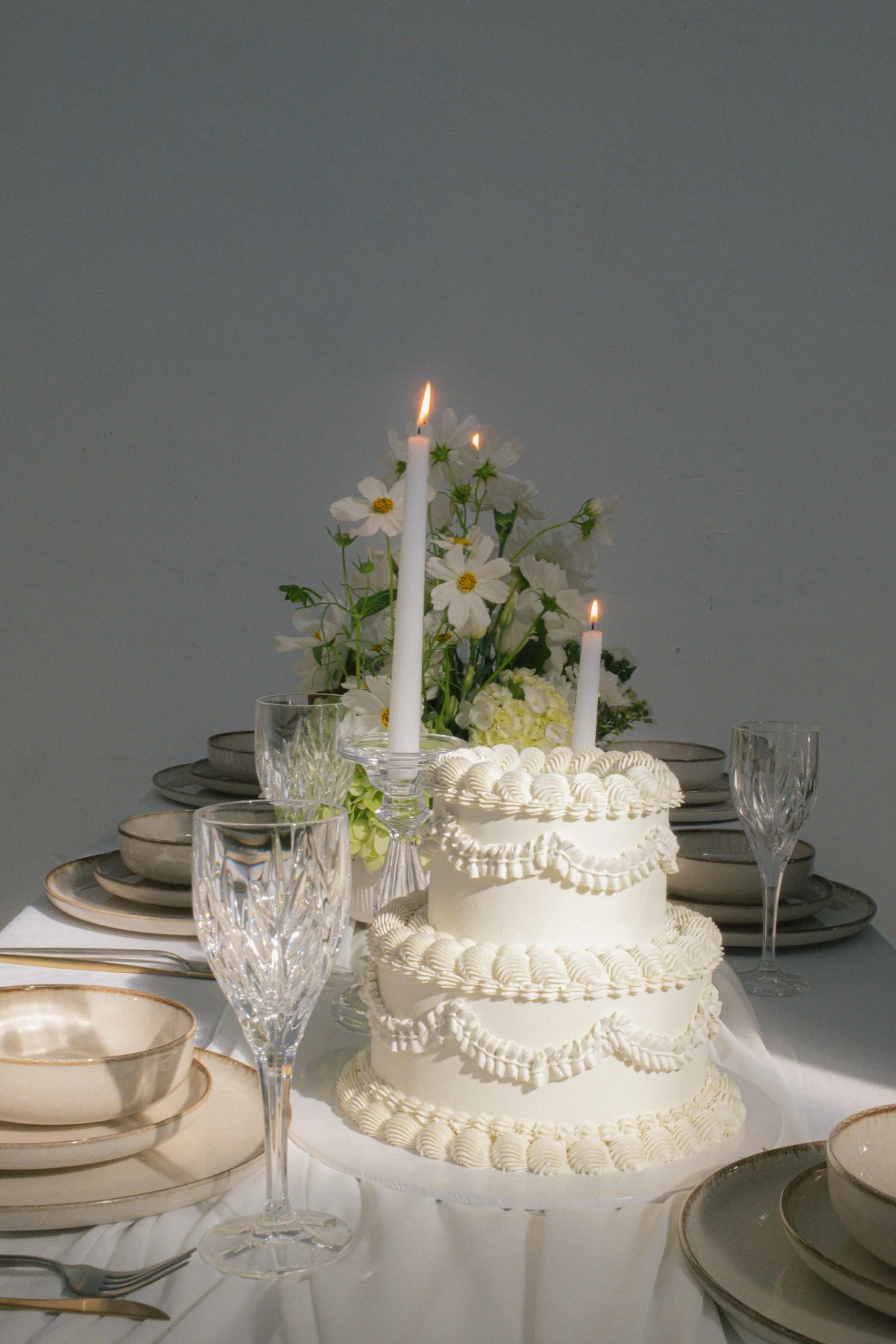 ivory tablescape with delicate wedding cake, candles and soft florals