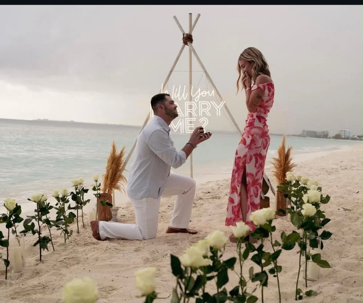 A Cayman beach proposal framed by a pathway of white roses
