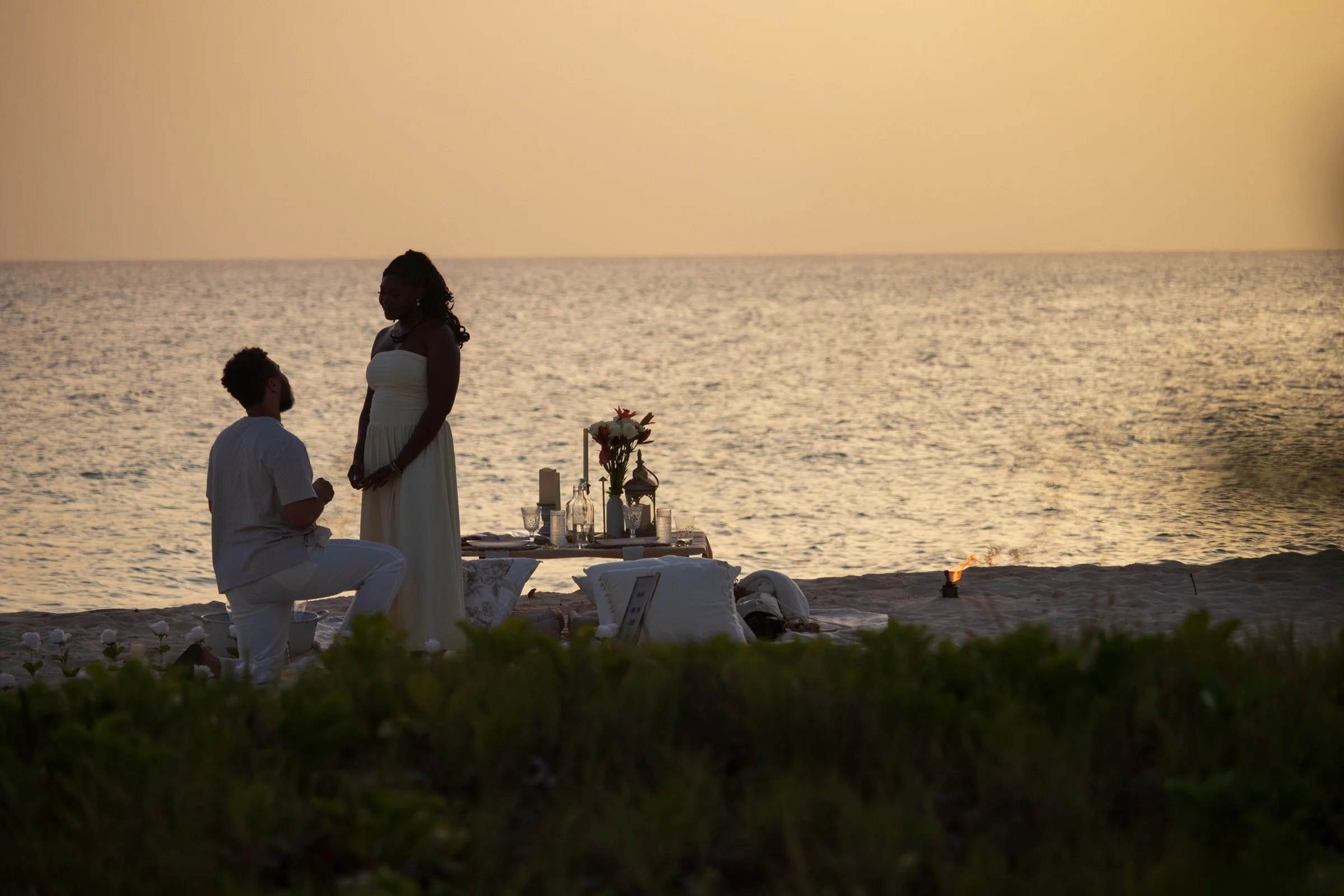 A golden-hour proposal framed by the ocean and a beautifully styled private setting.