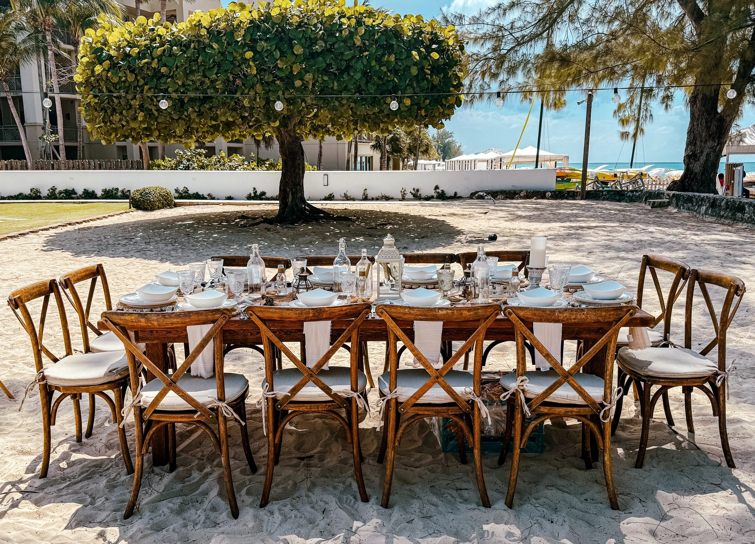 A complete daytime picnic table arranged beneath trees at a private Grand Cayman beachfront property.