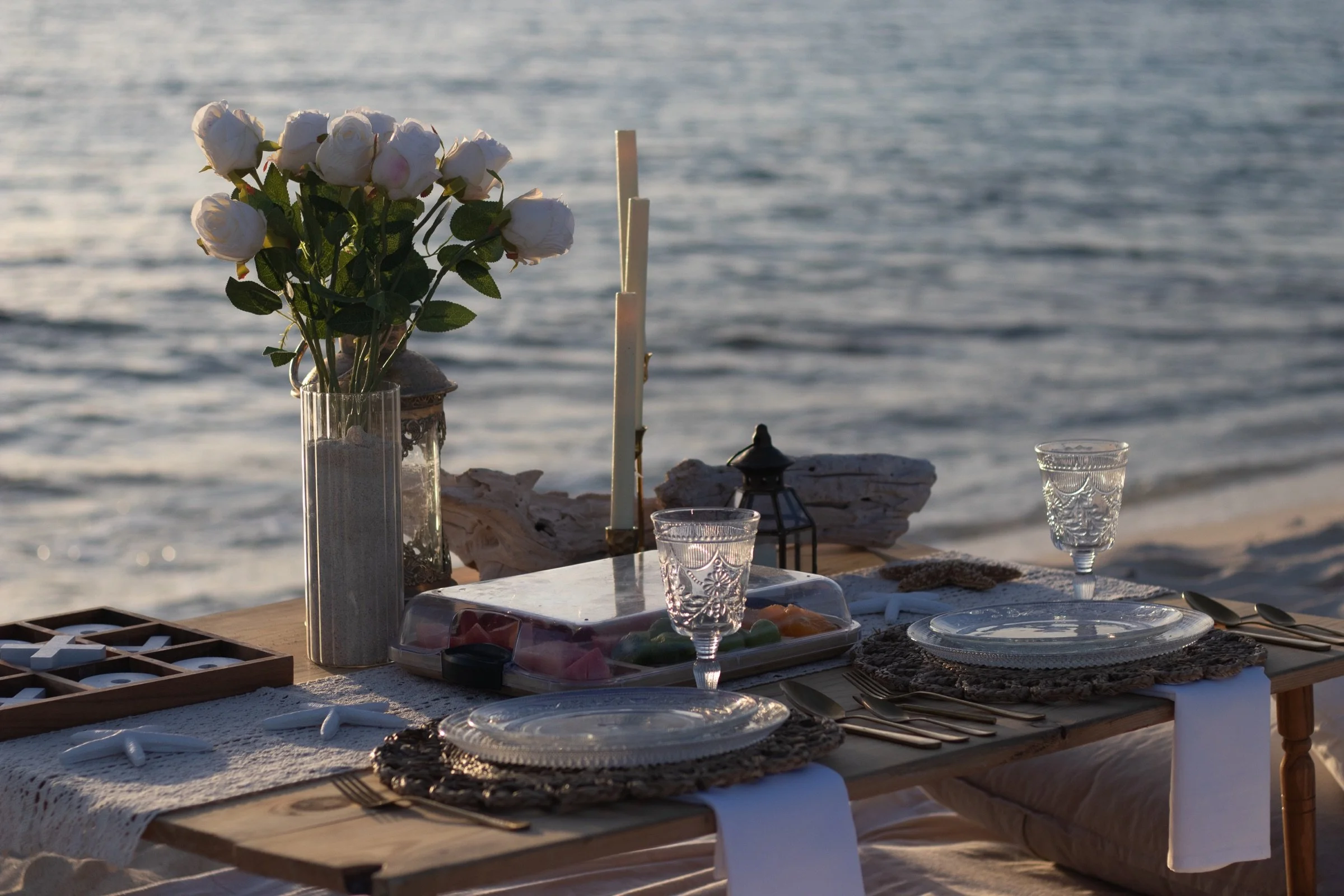 A kneeling proposal shown within the full styled beach setting at sunset.