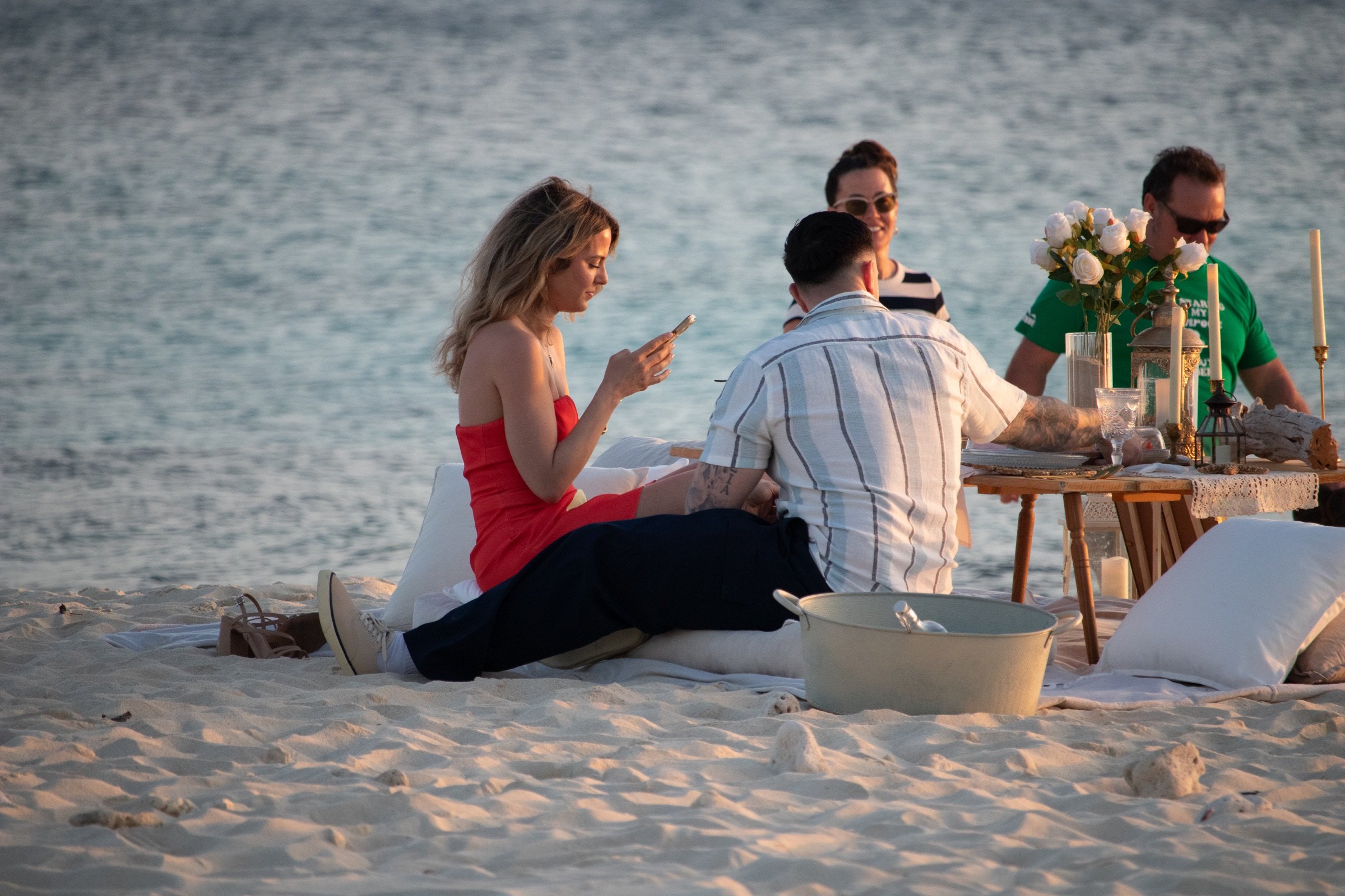 A newly engaged couple celebrating together at their private beach picnic setting.