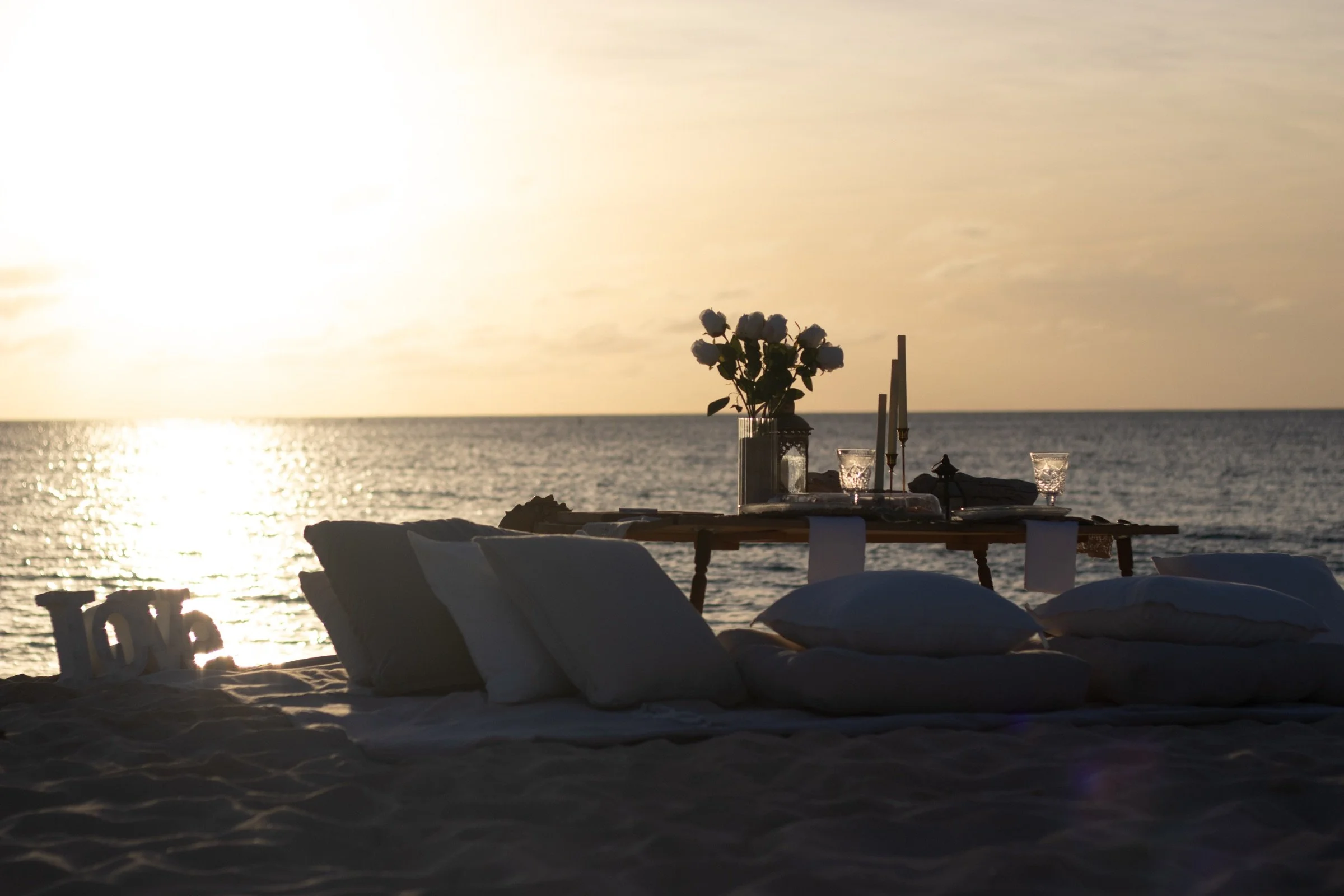 A private proposal setting arranged on the sand as the sun lowers over the Caribbean Sea.