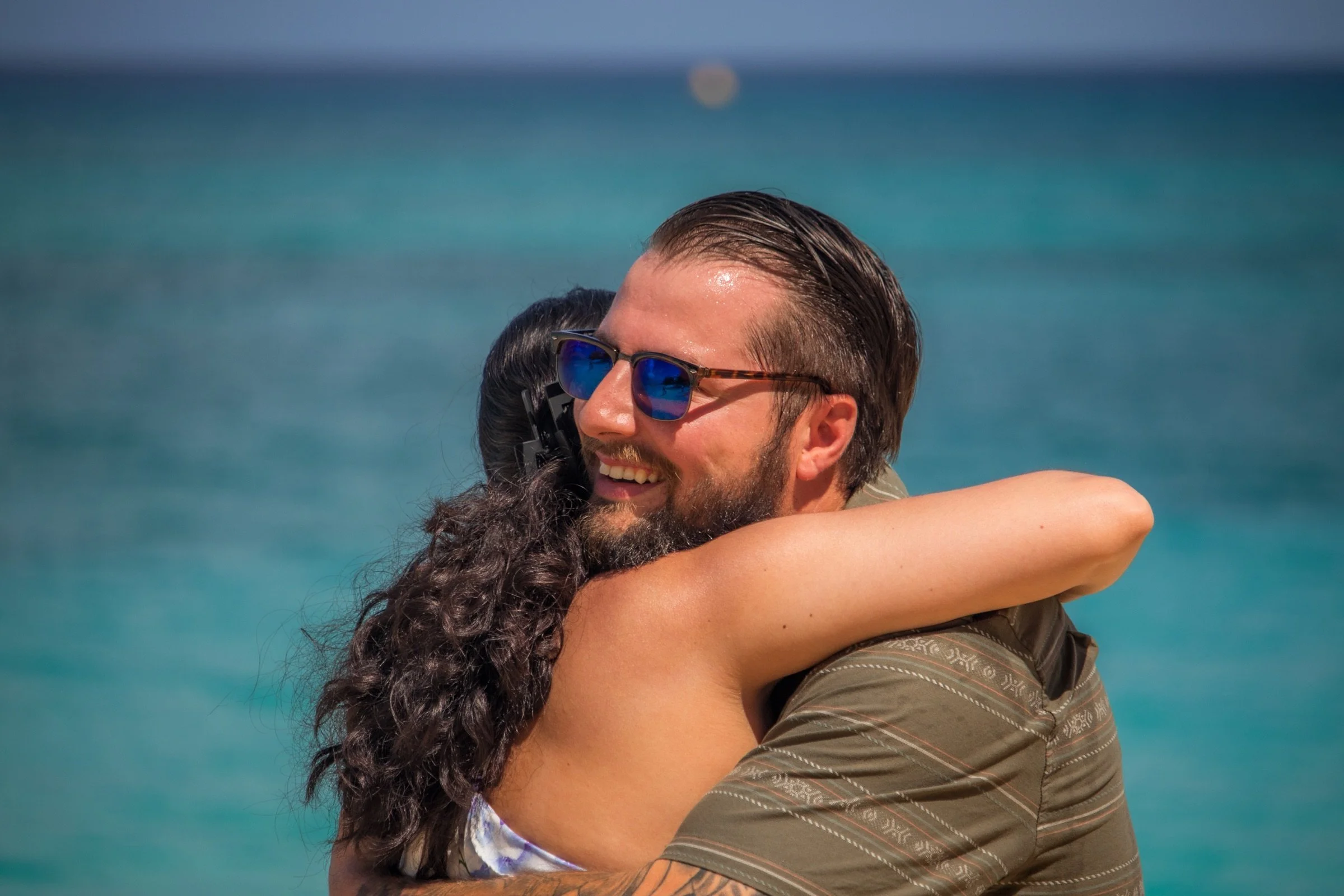 A couple sharing an emotional embrace immediately after their Cayman beach proposal.