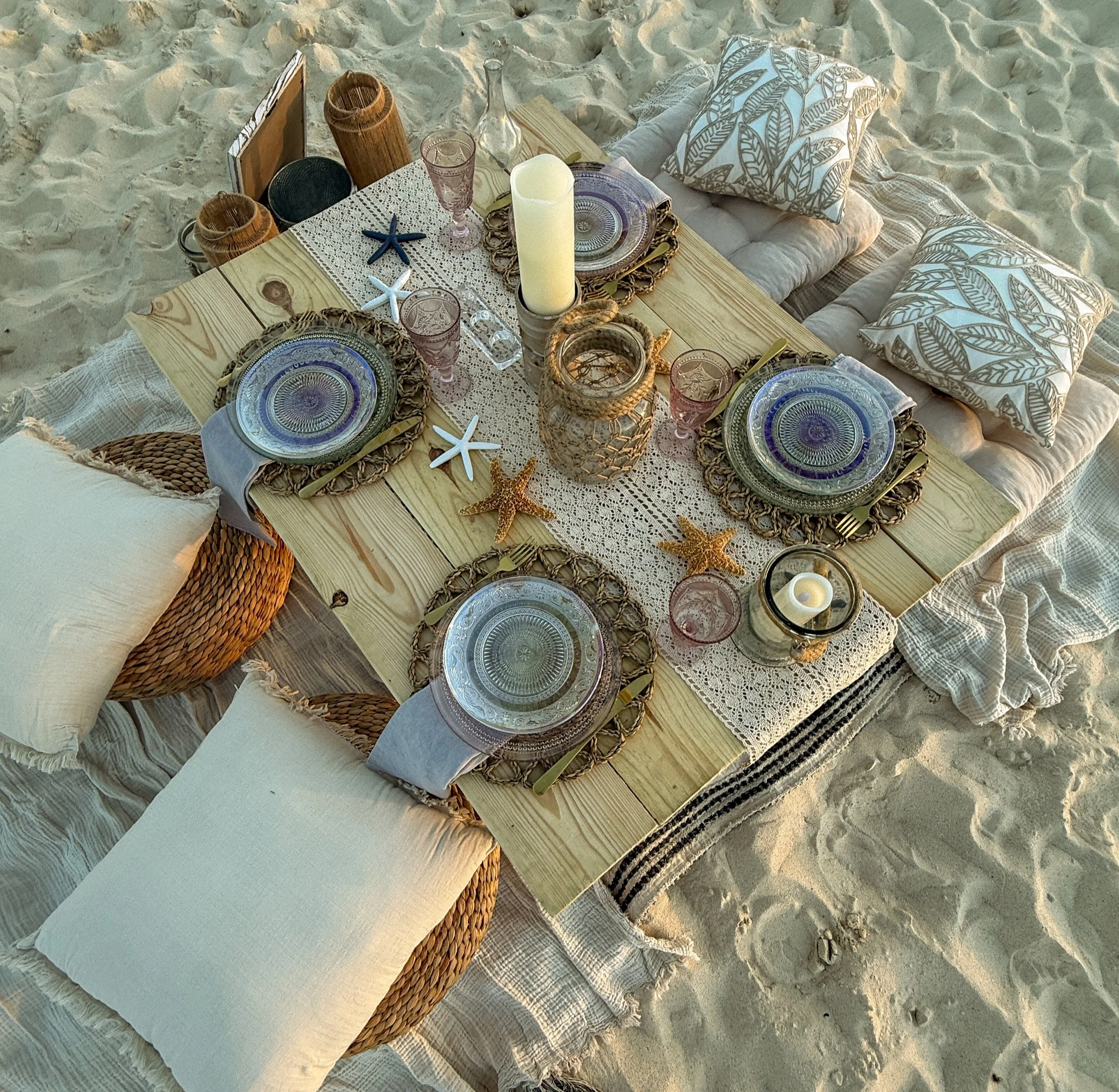 A blue and neutral coastal tablescape photographed from above on the sand.