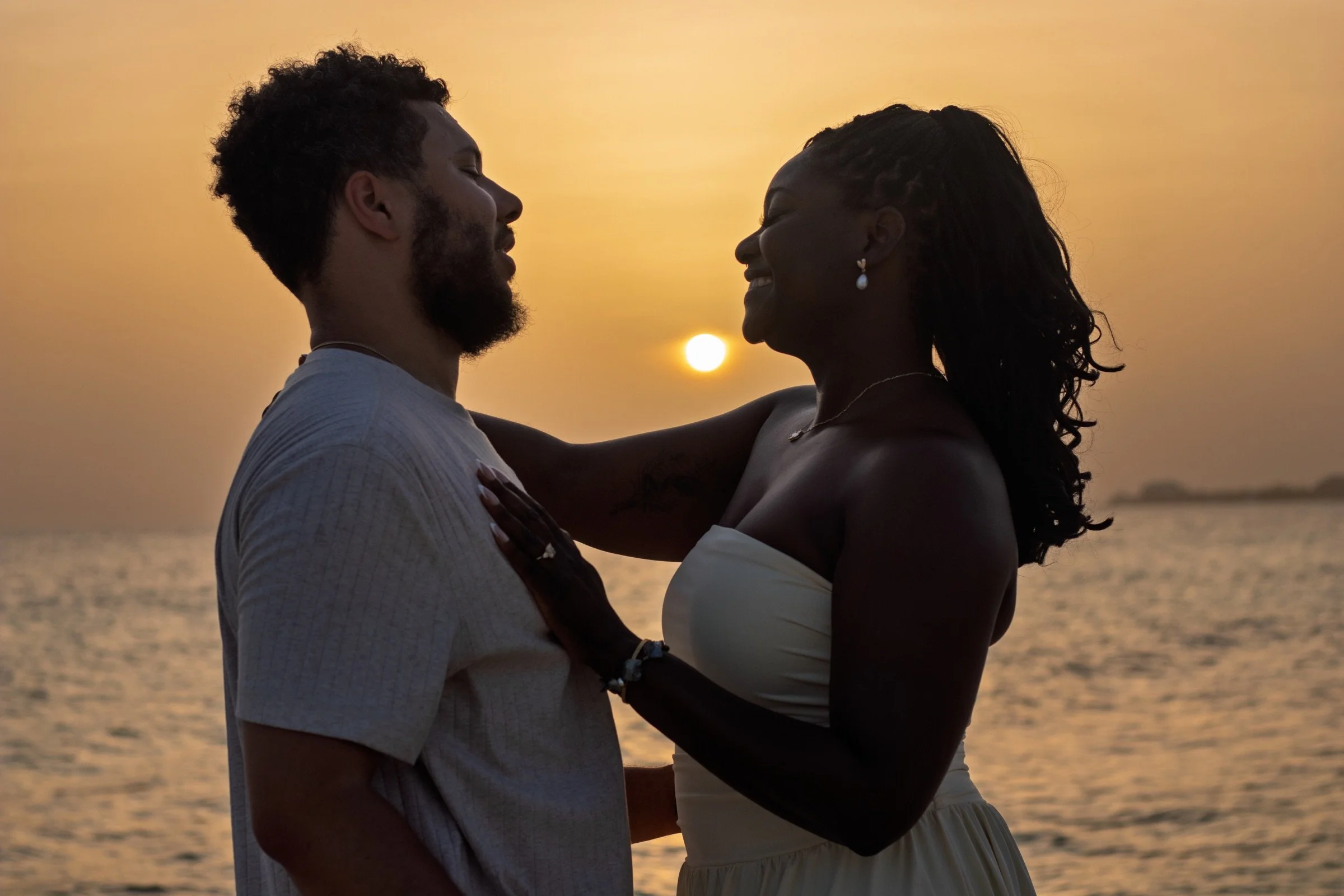 A couple embracing in silhouette as the sun sets over their Grand Cayman proposal.
